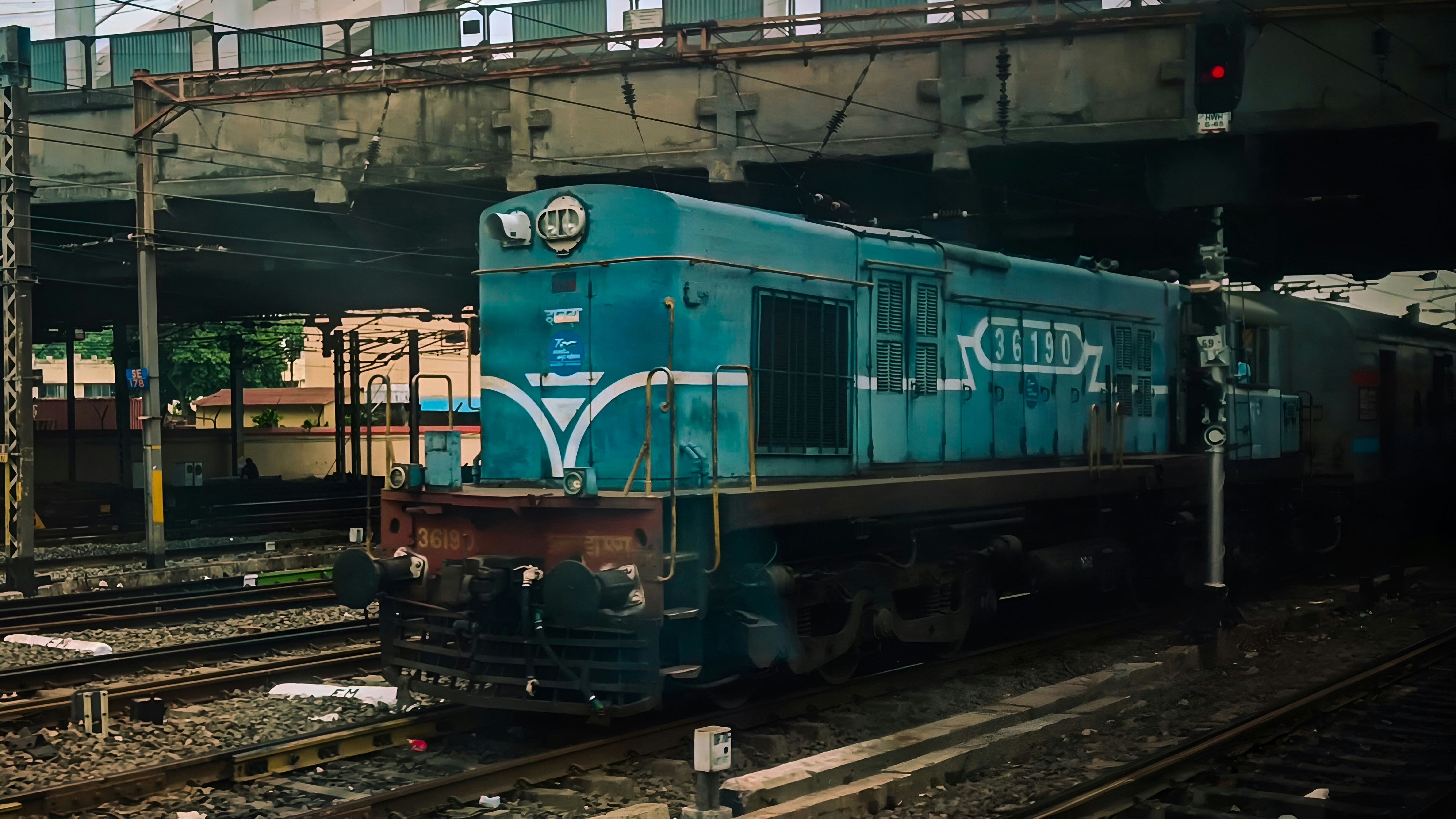 A blue train passes beneath an overpass