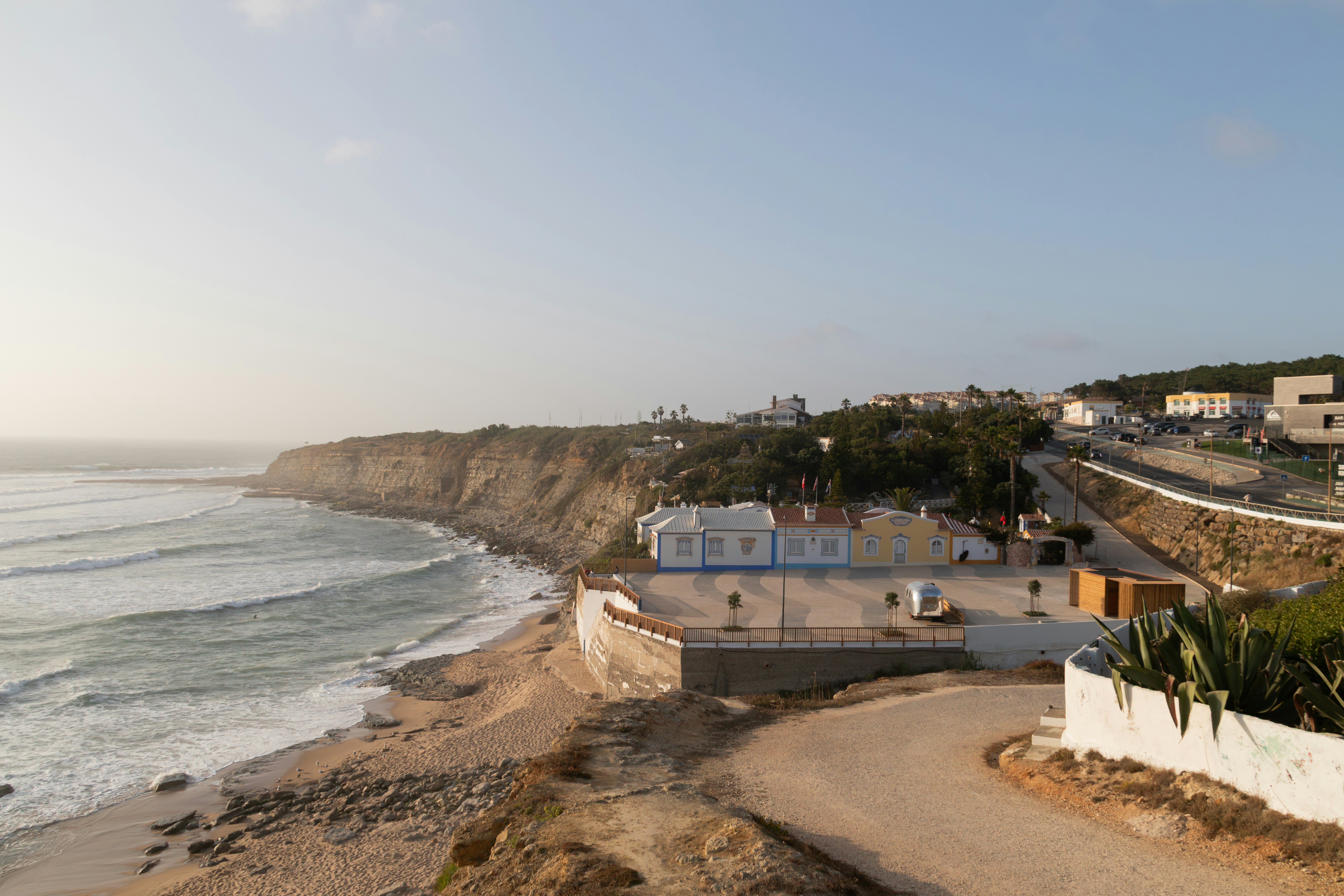 Coastal landscape with beach, buildings, and cliffs.