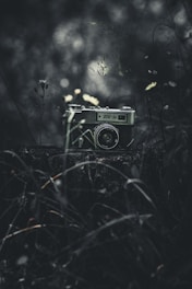 A vintage camera sits in a dark, moody setting.