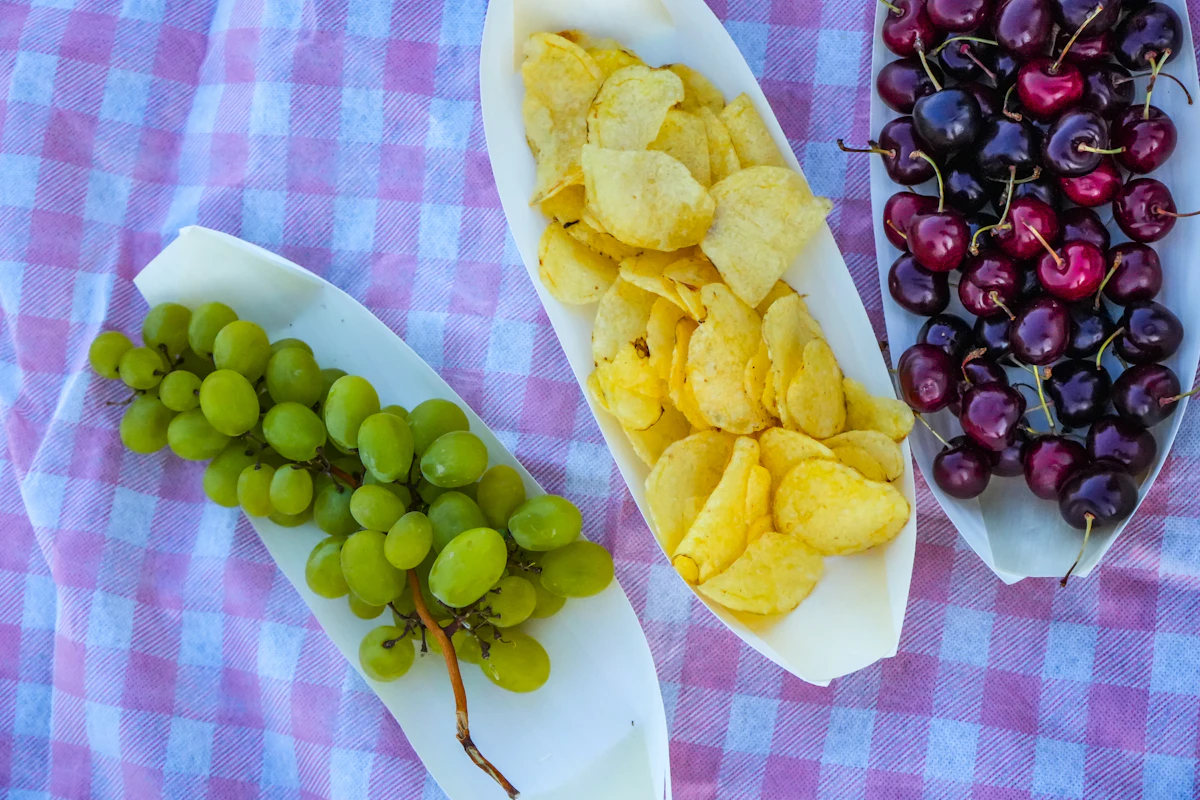 Fruit and snacks arranged on a checkered picnic blanket