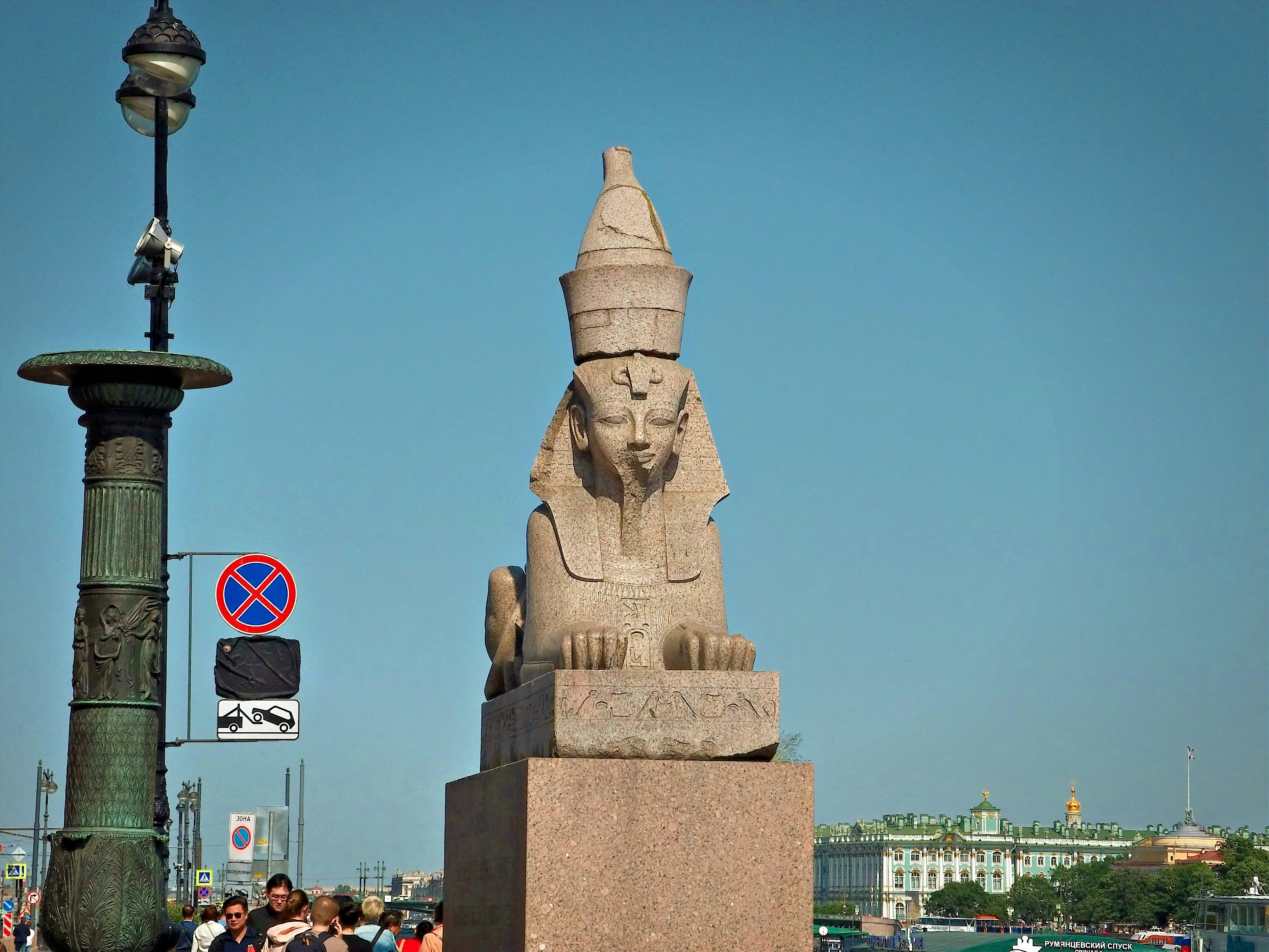 A stone sphinx statue stands tall under the blue sky.