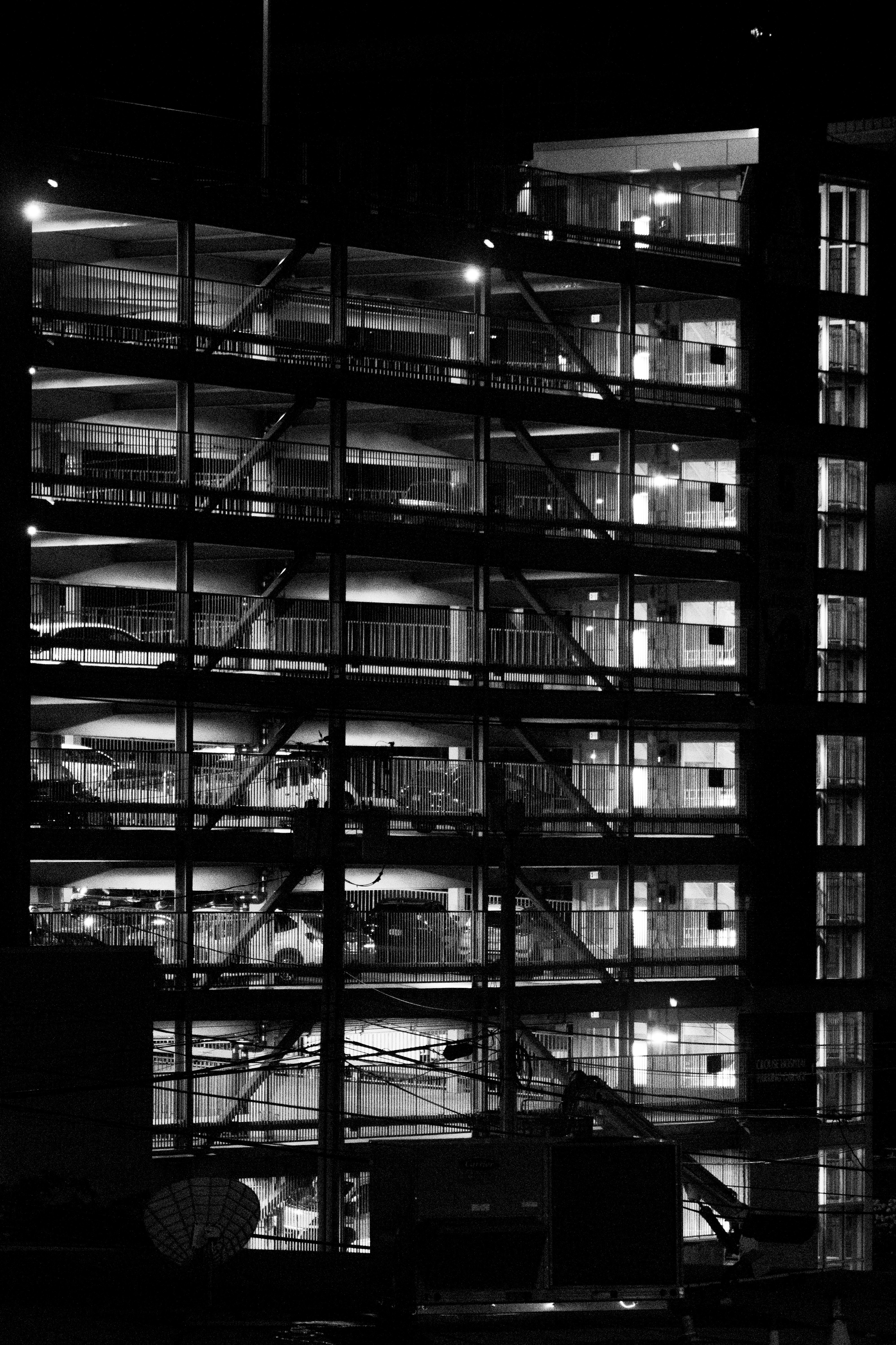 Cars parked in a lit-up, multi-story parking garage.