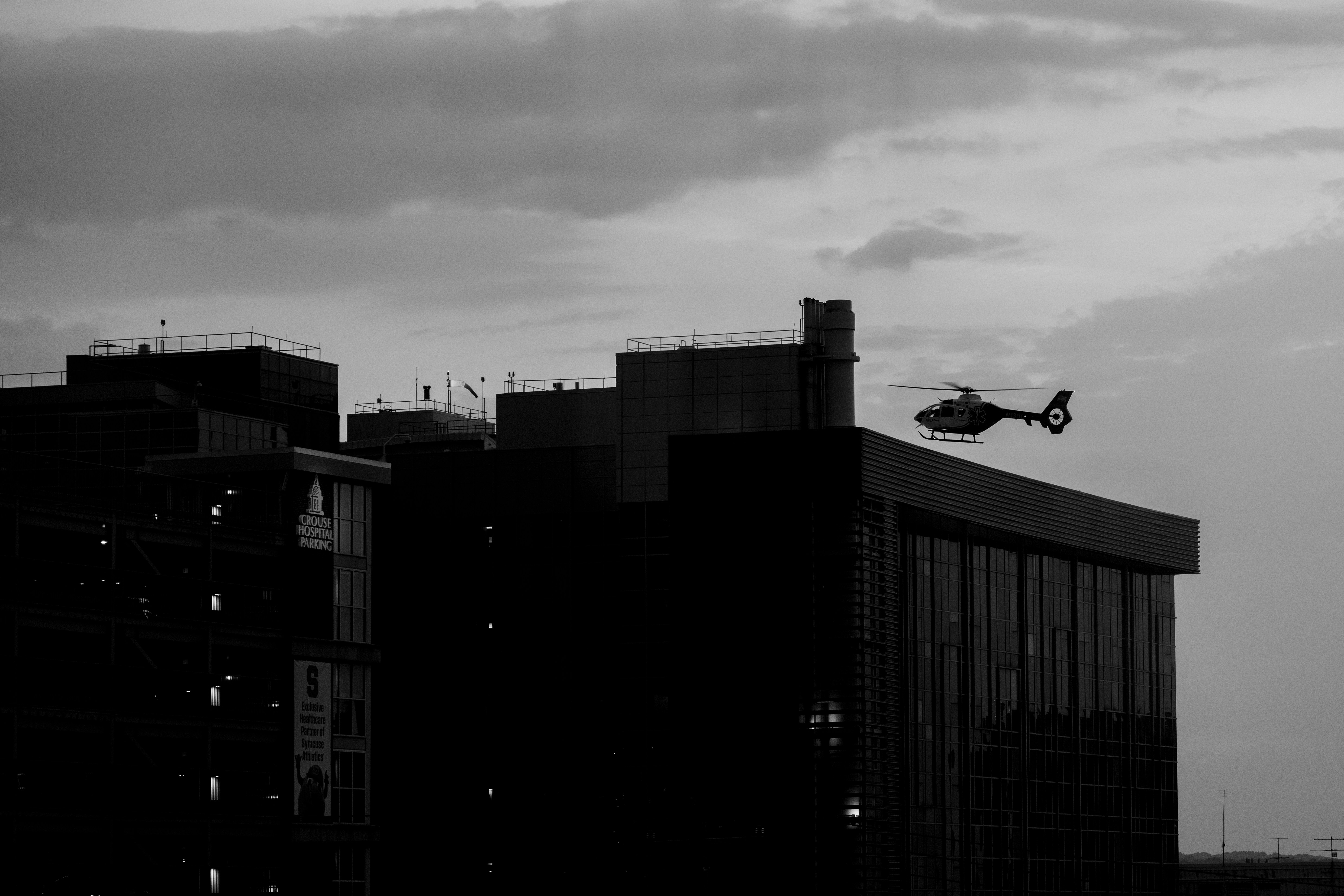 A helicopter flies past a building at dusk.