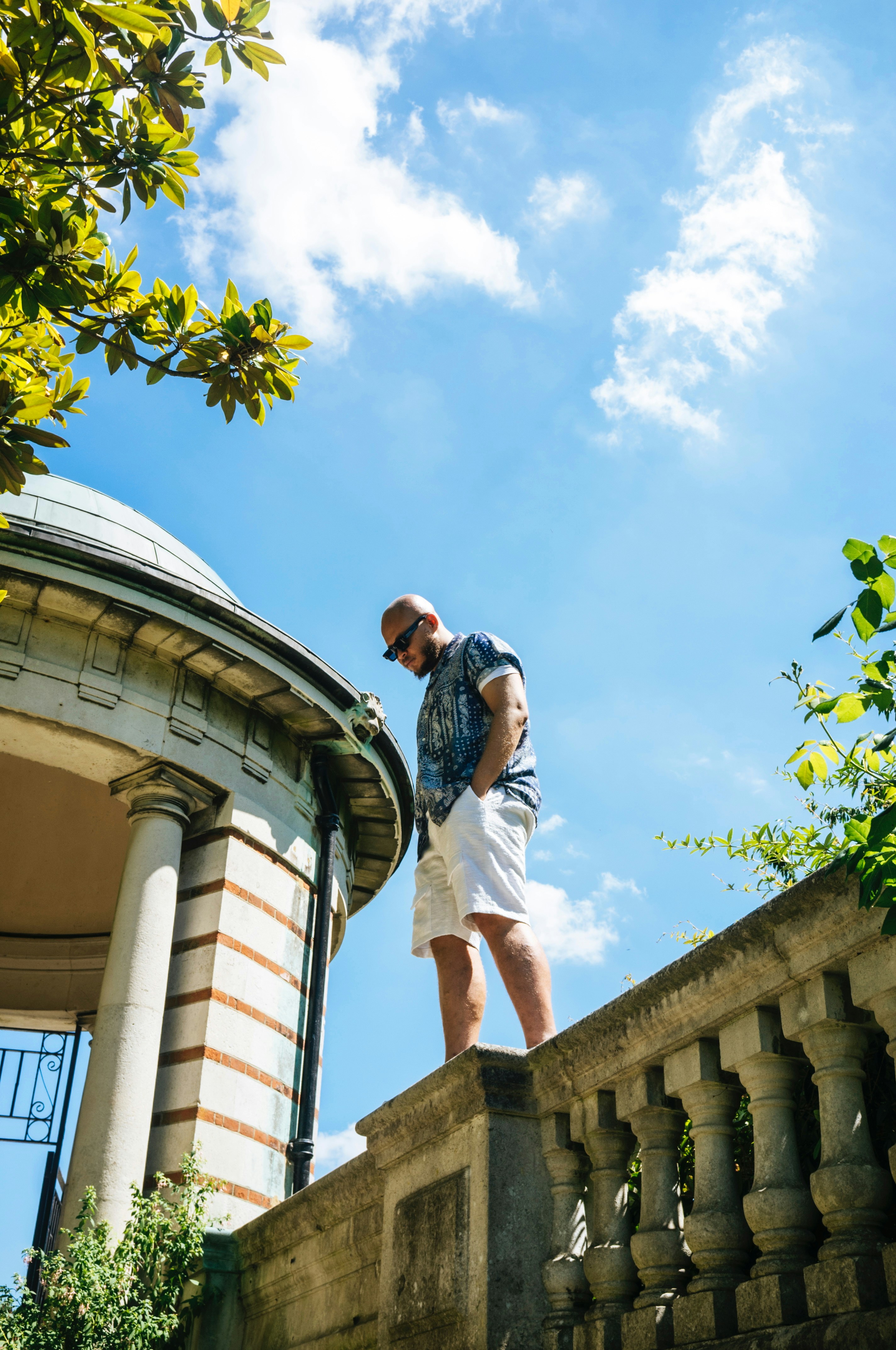 Man stands on a wall with a blue sky backdrop.