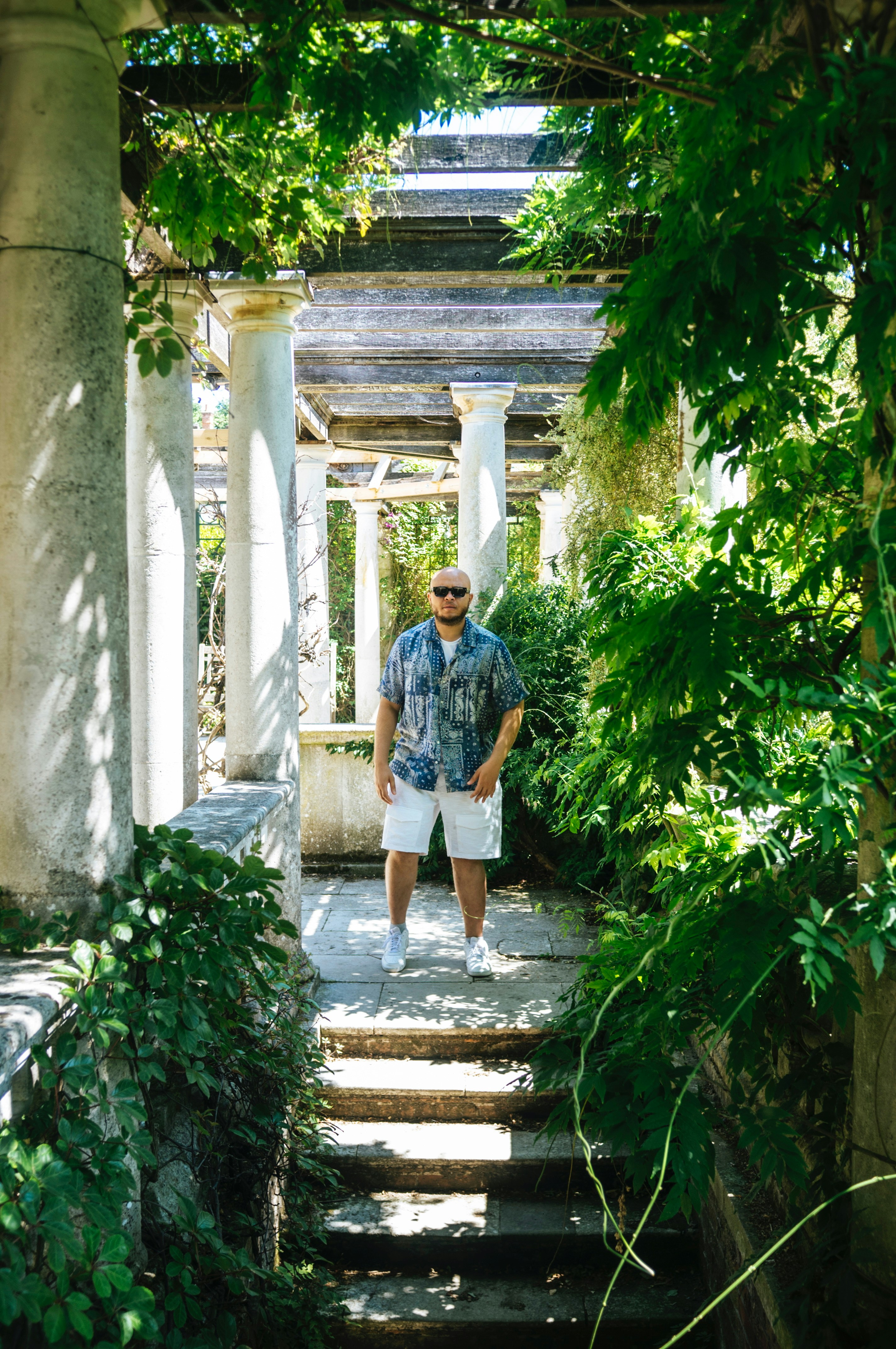 A man stands in a beautiful, leafy garden.
