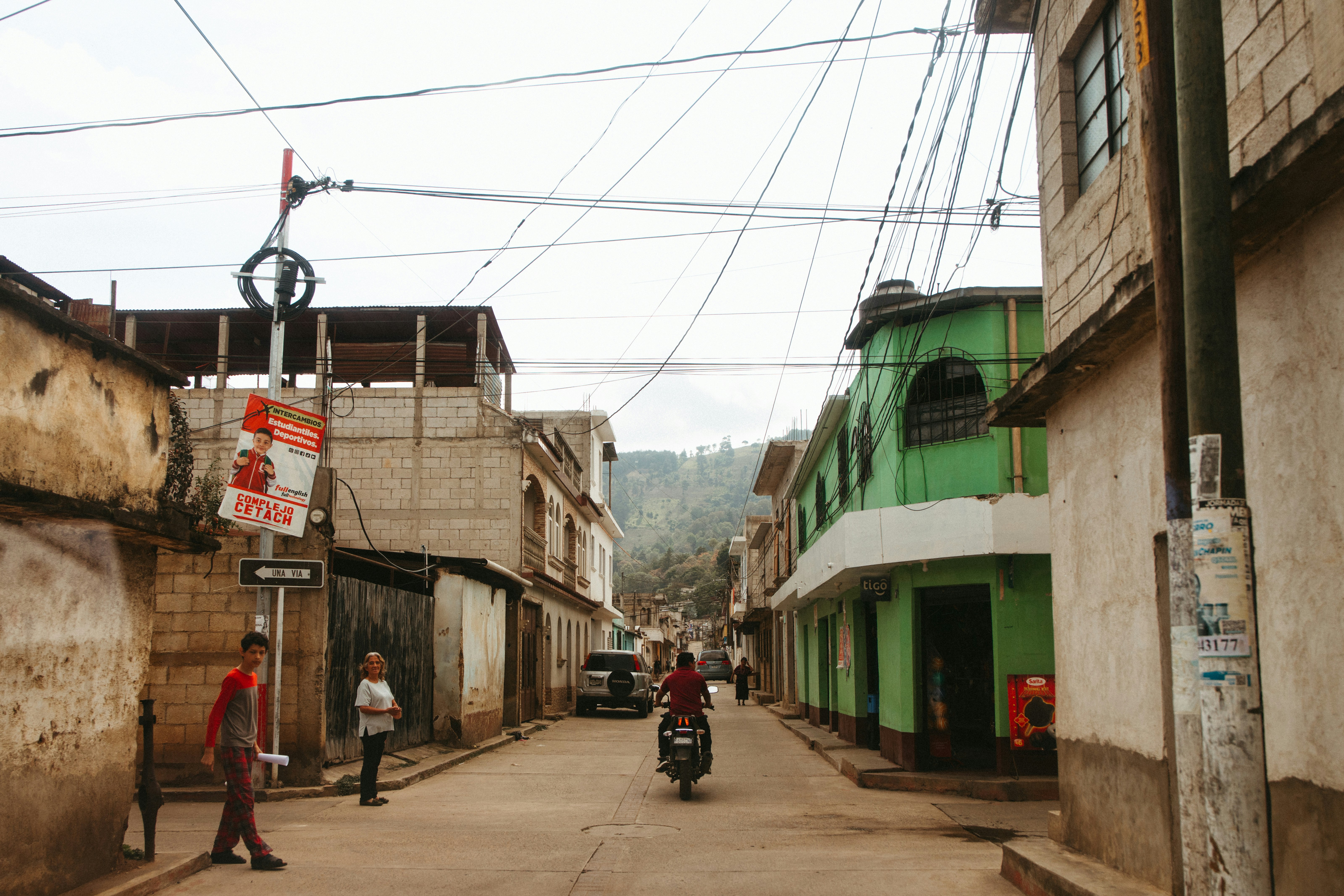A rural street shows buildings and overhead wires.