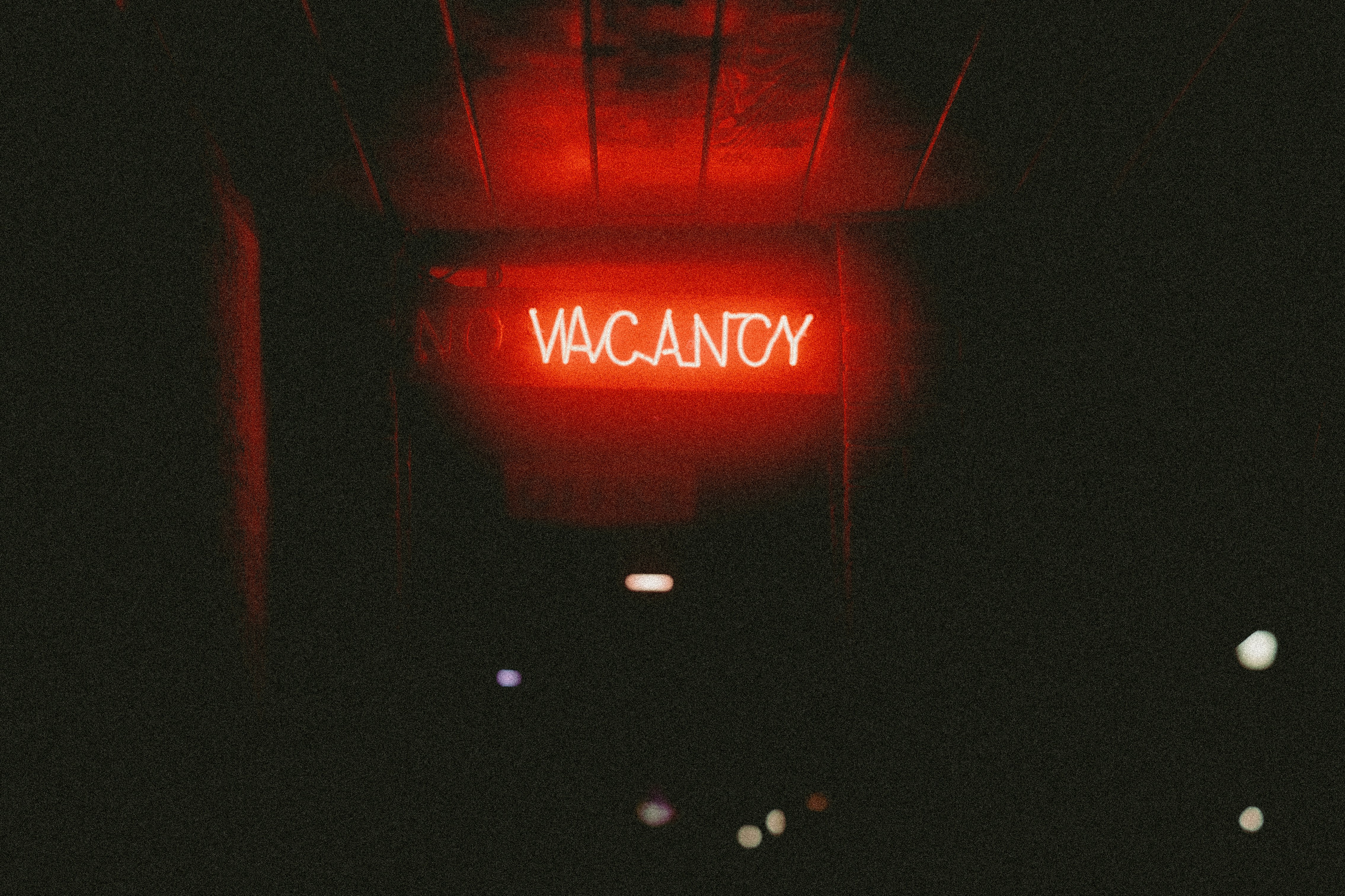 A red "vacancy" neon sign in darkness.