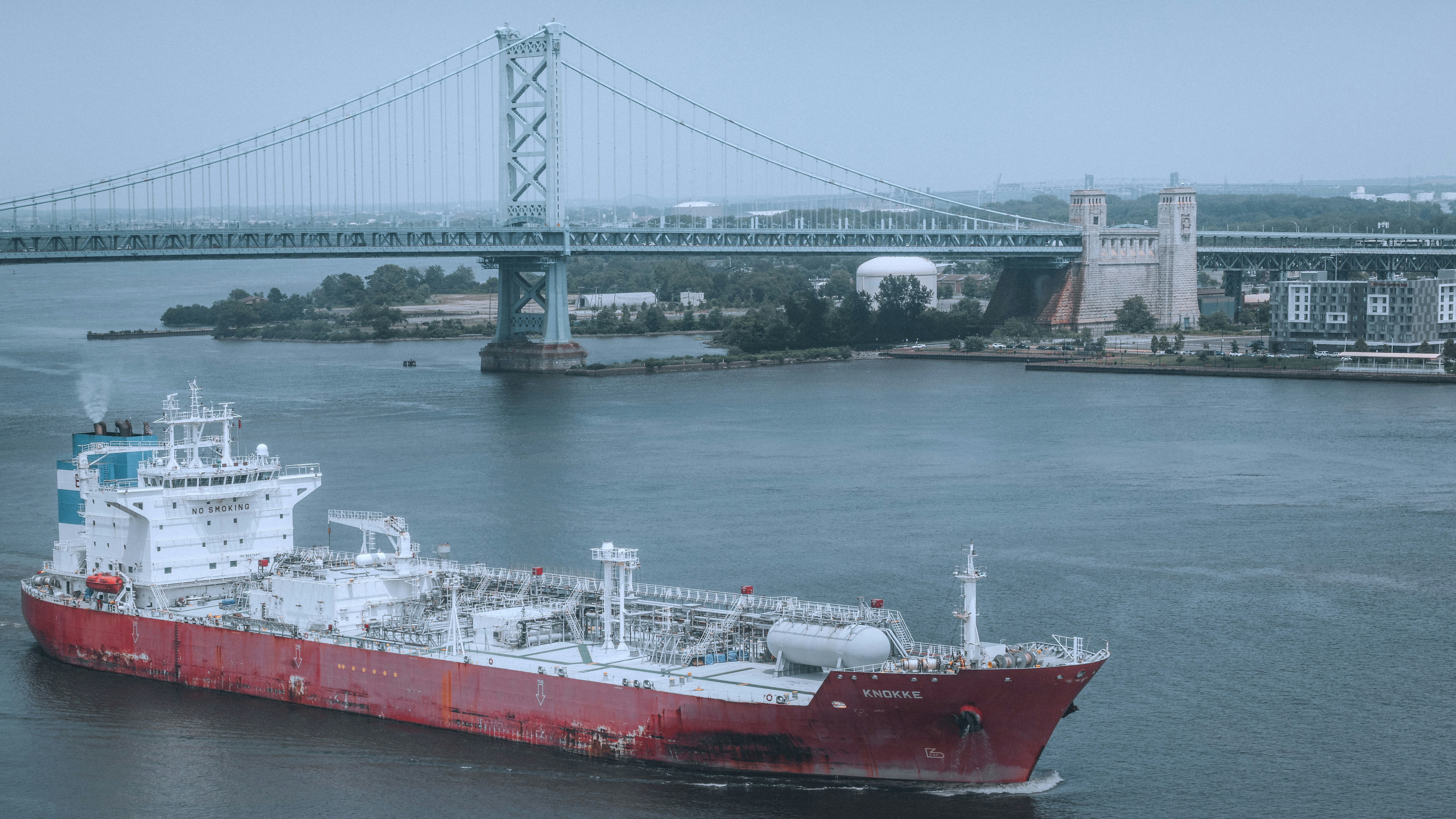 A ship sails under a bridge in the harbor.