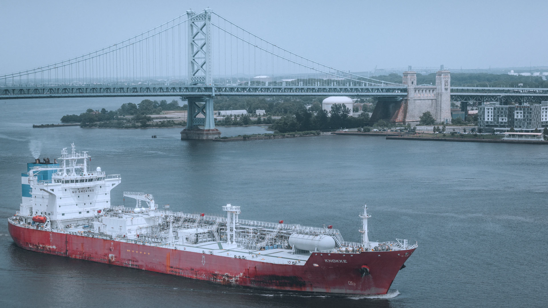 A ship sails under a bridge in the harbor