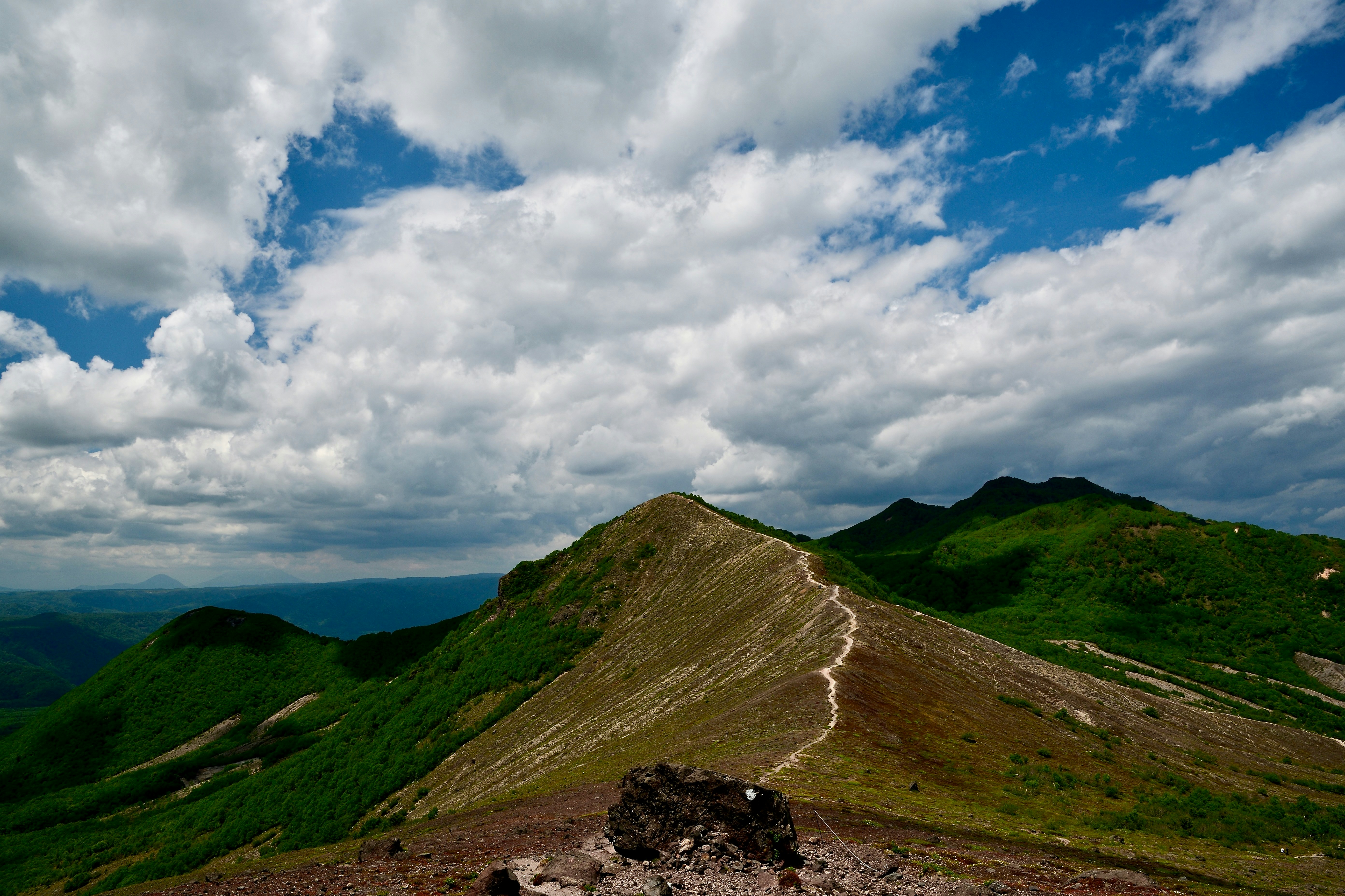 Mountains and a trail under a cloudy sky.