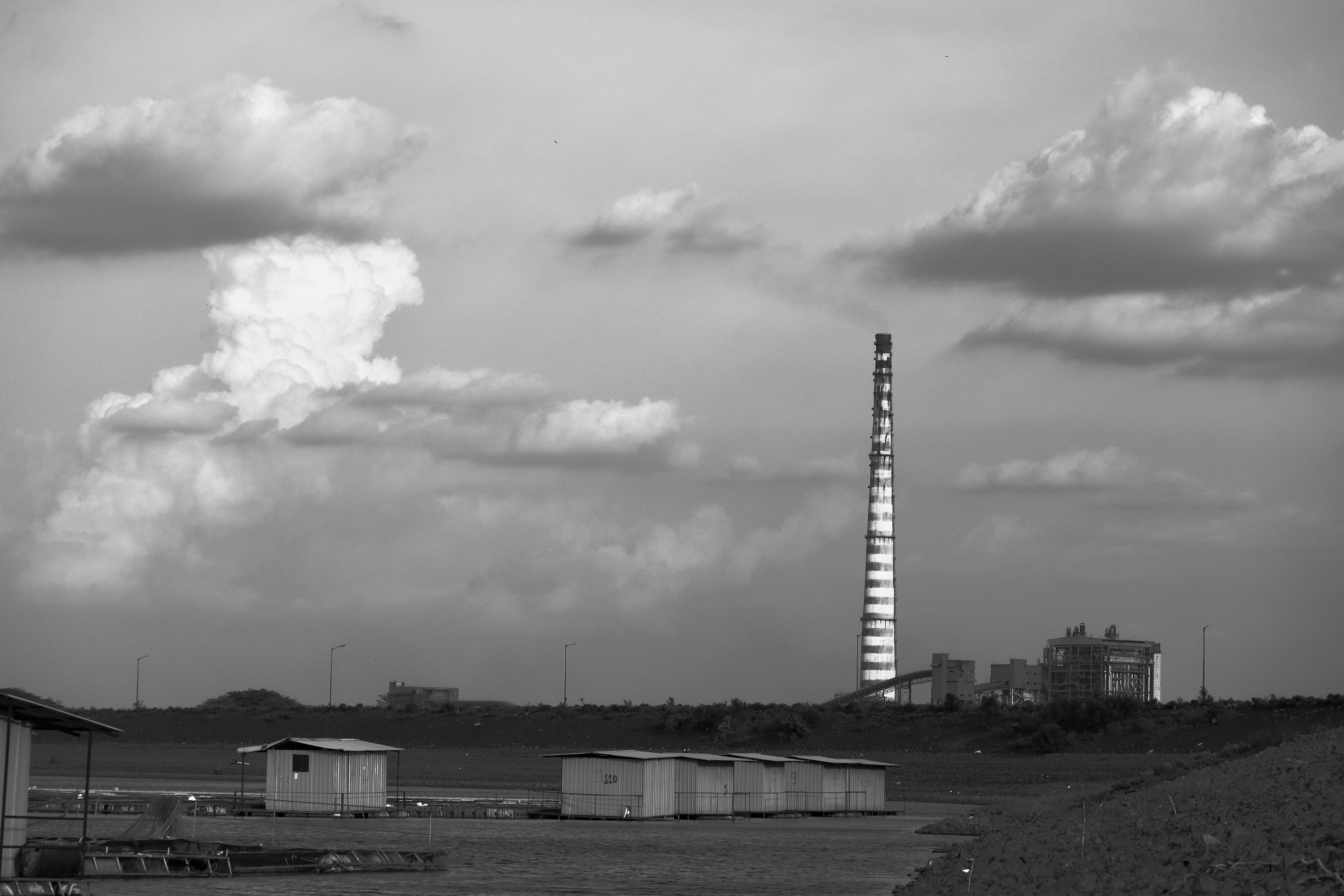 Ein Schornstein thront über der Fabrik und dem bewölkten Himmel.