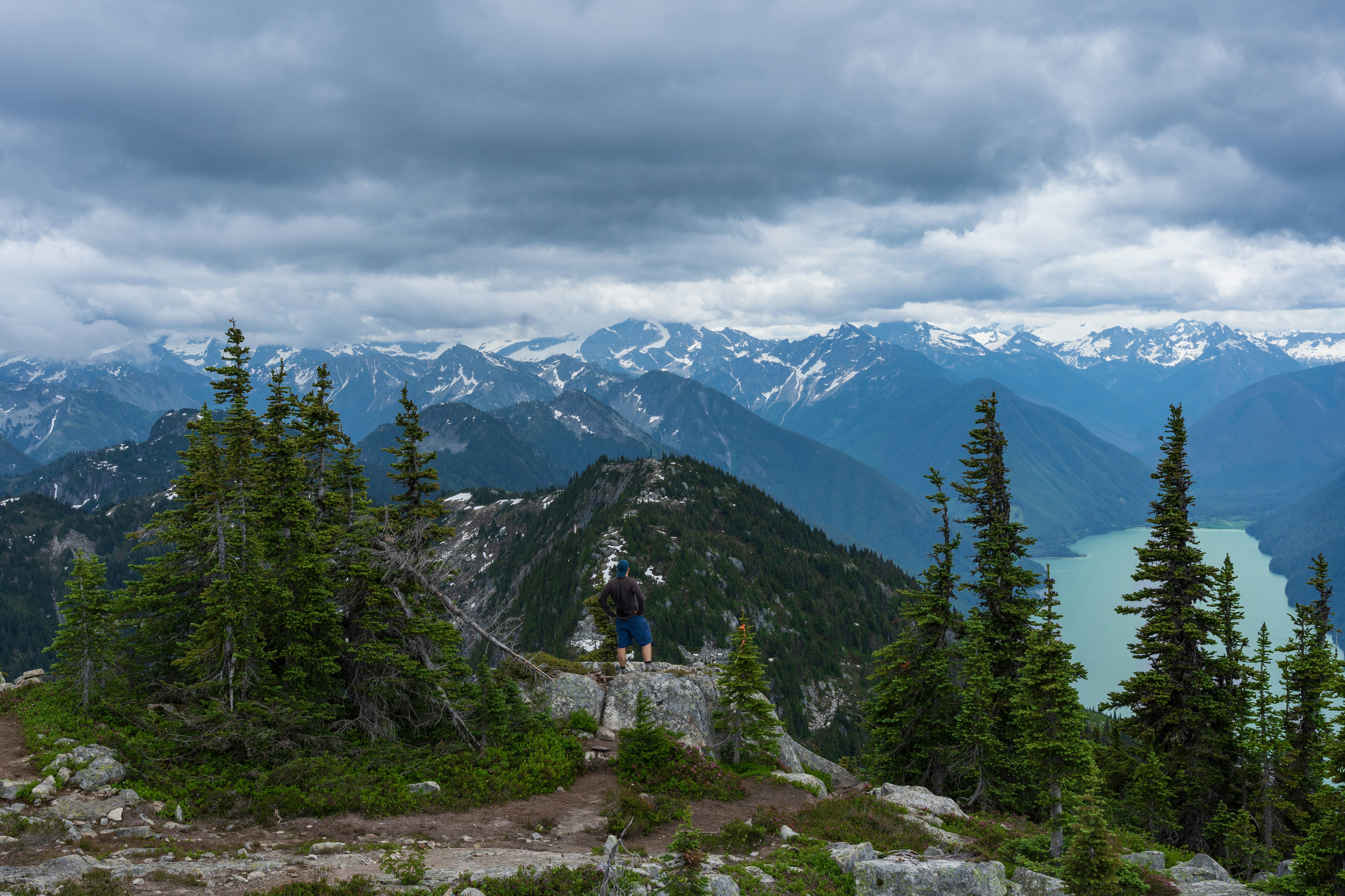 A hiker stands atop a mountain peak.