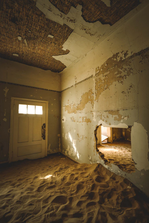 Sand pouring through doorframe at Kolmanskop