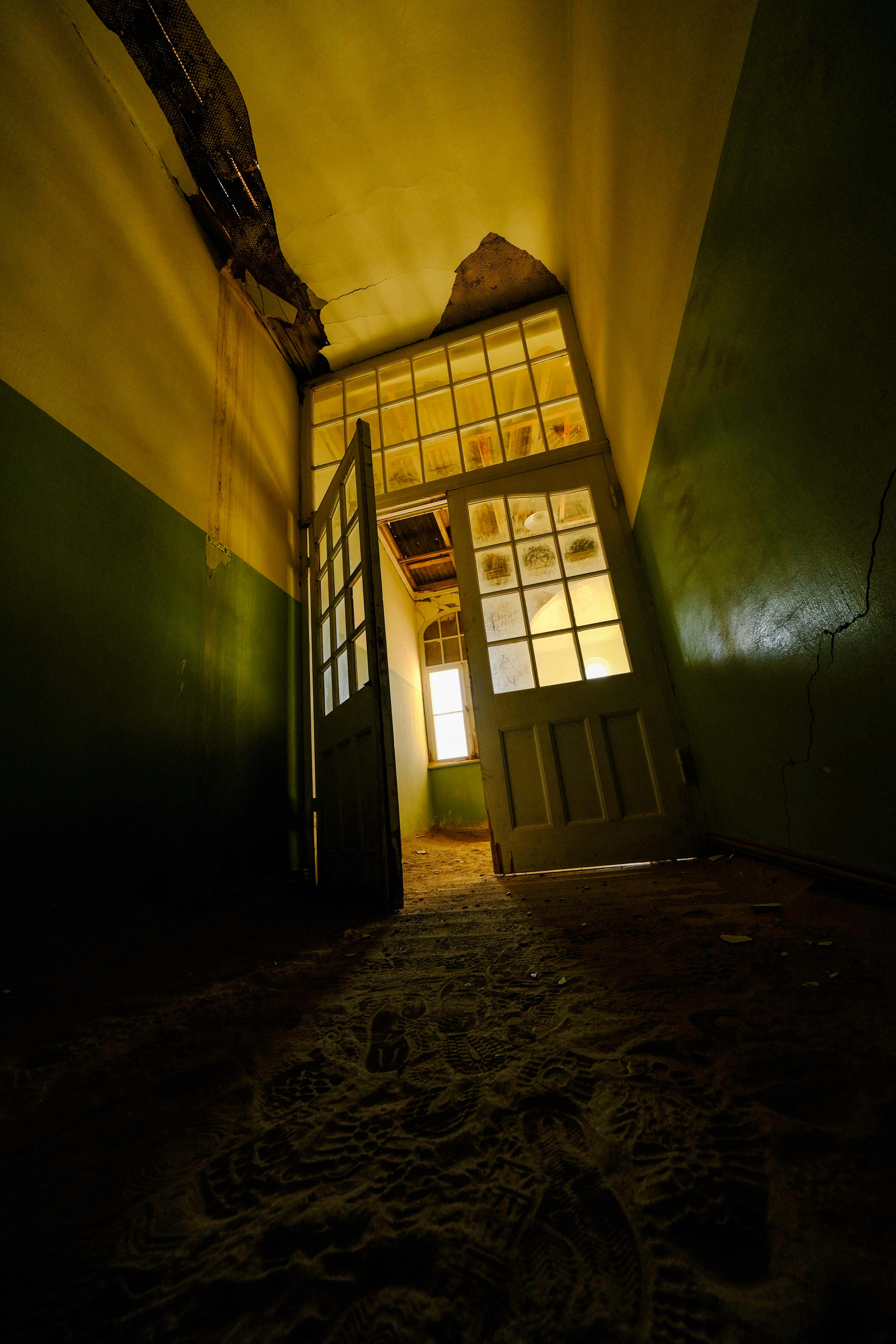 壊れた出入り口と日光が差し込む廃墟の廊下。の写真 – Unsplash