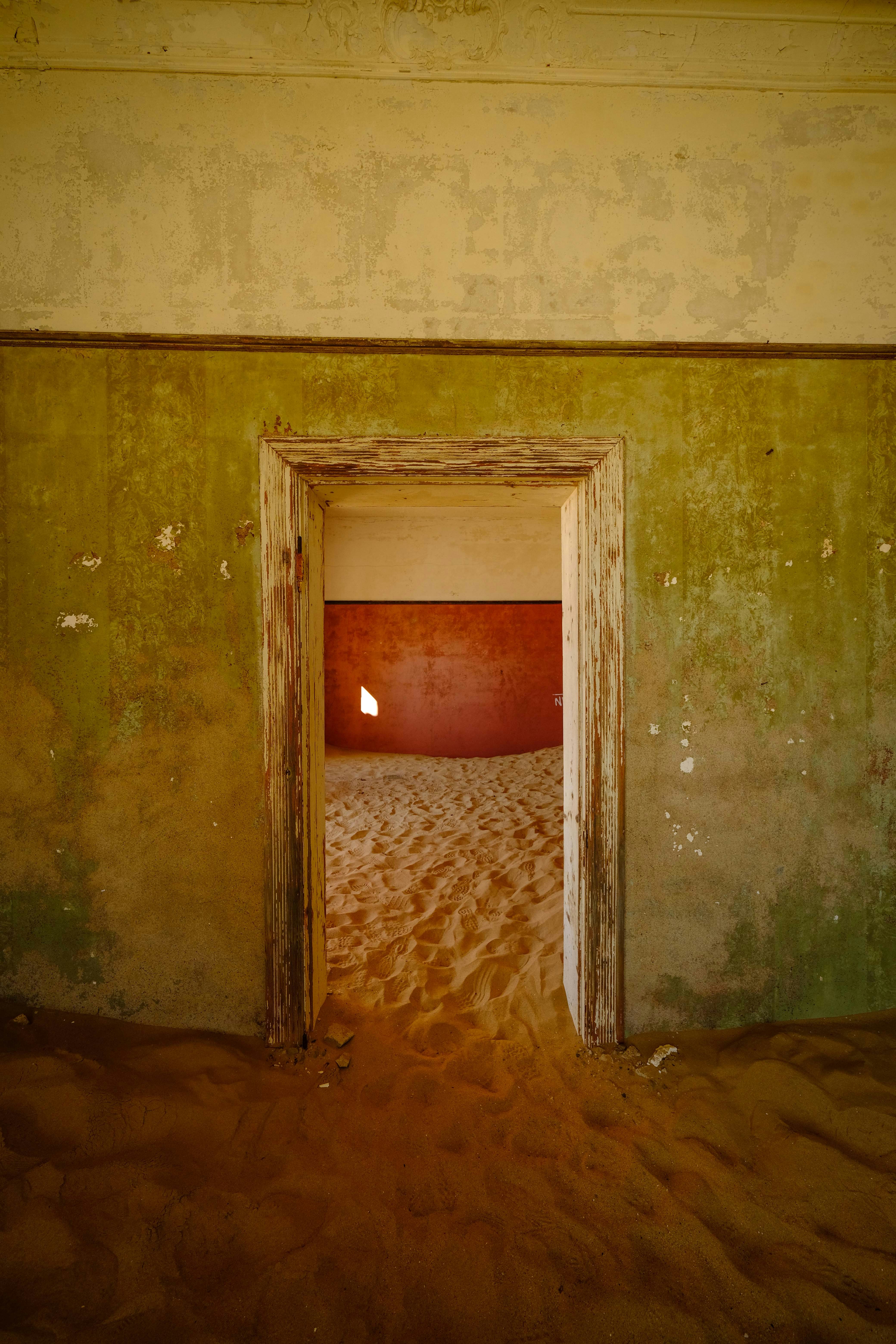 Sand fills an abandoned building's doorway and rooms.