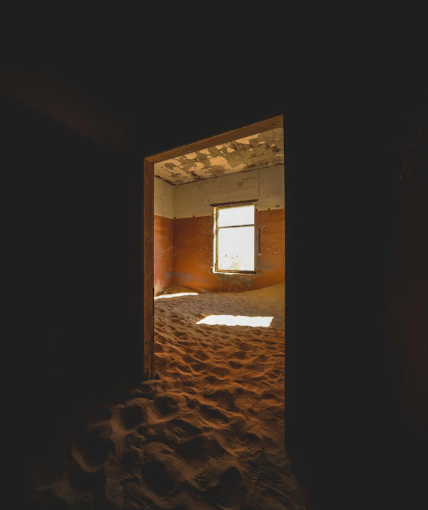 Morning light streaming through a broken window at Kolmanskop
