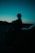 A person sits silhouetted on a car.