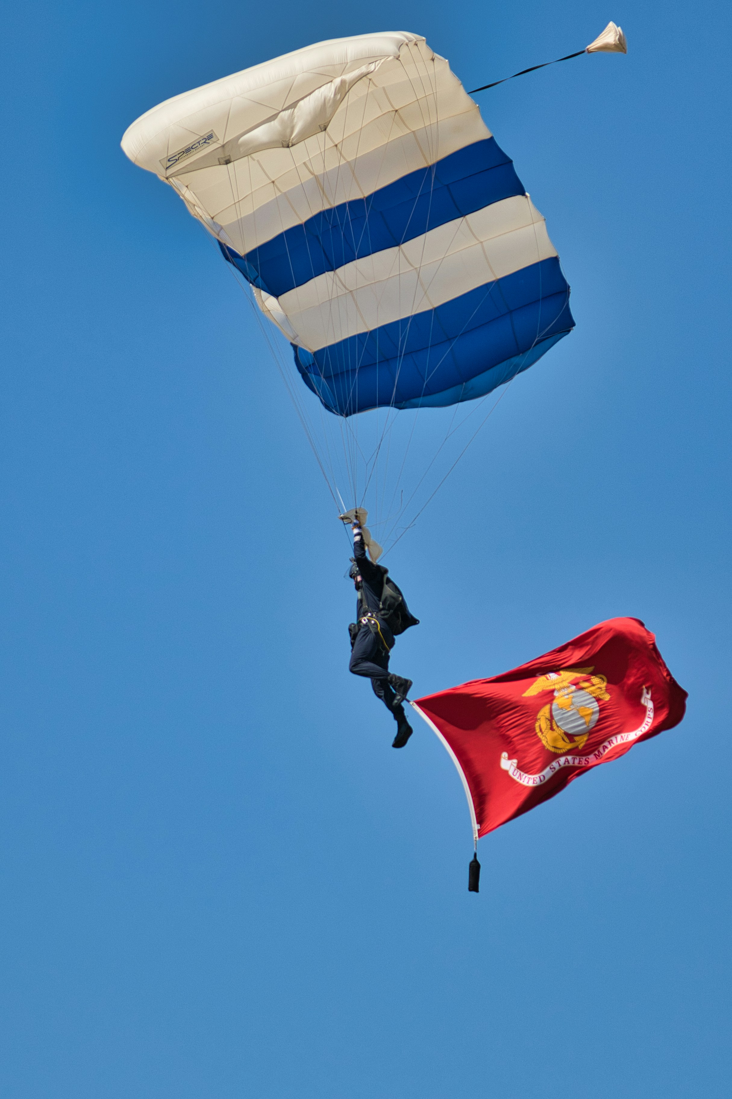 A parachutist descends with a united states marine corps flag.