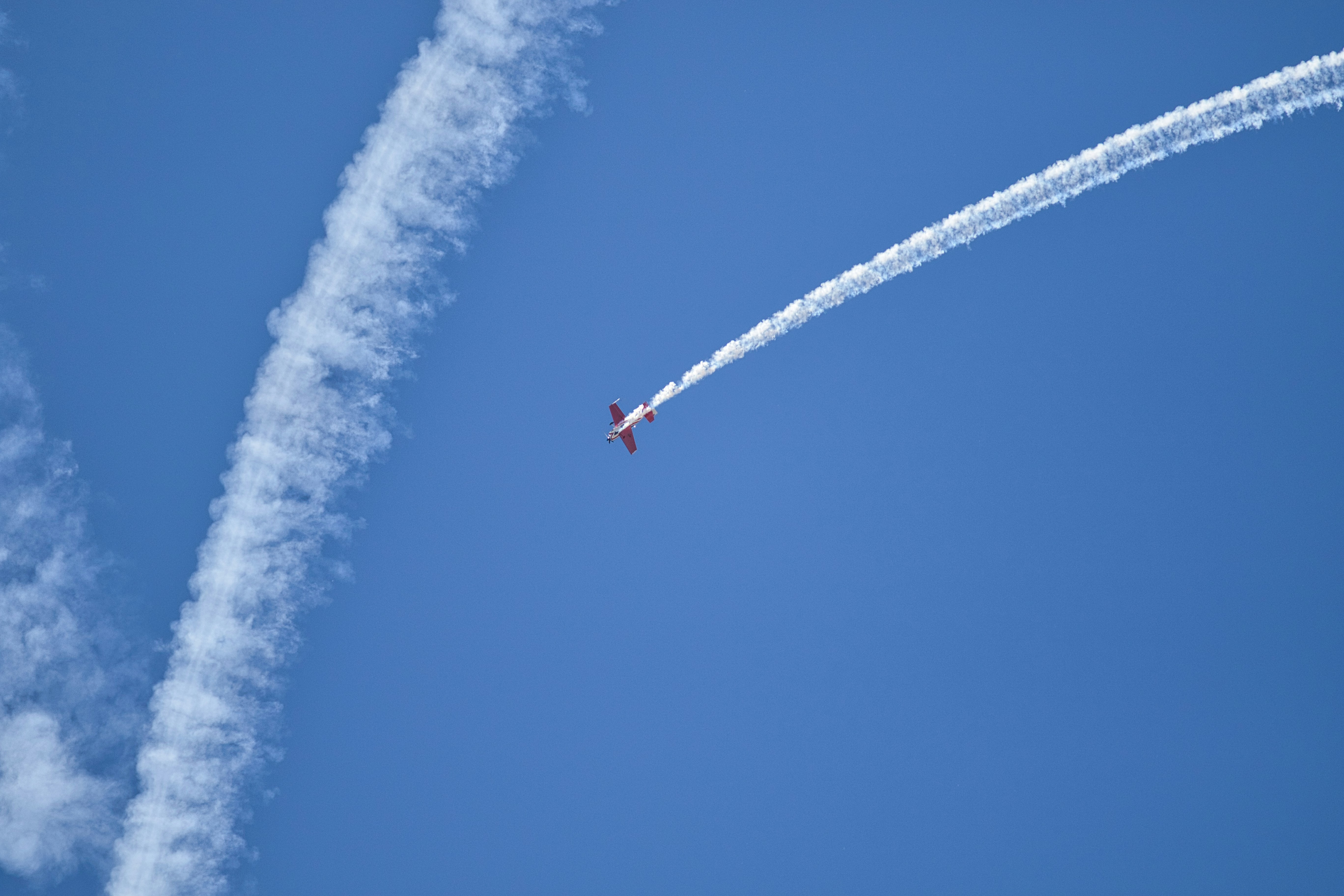 Un avion effectue des cascades dans le ciel bleu vif.