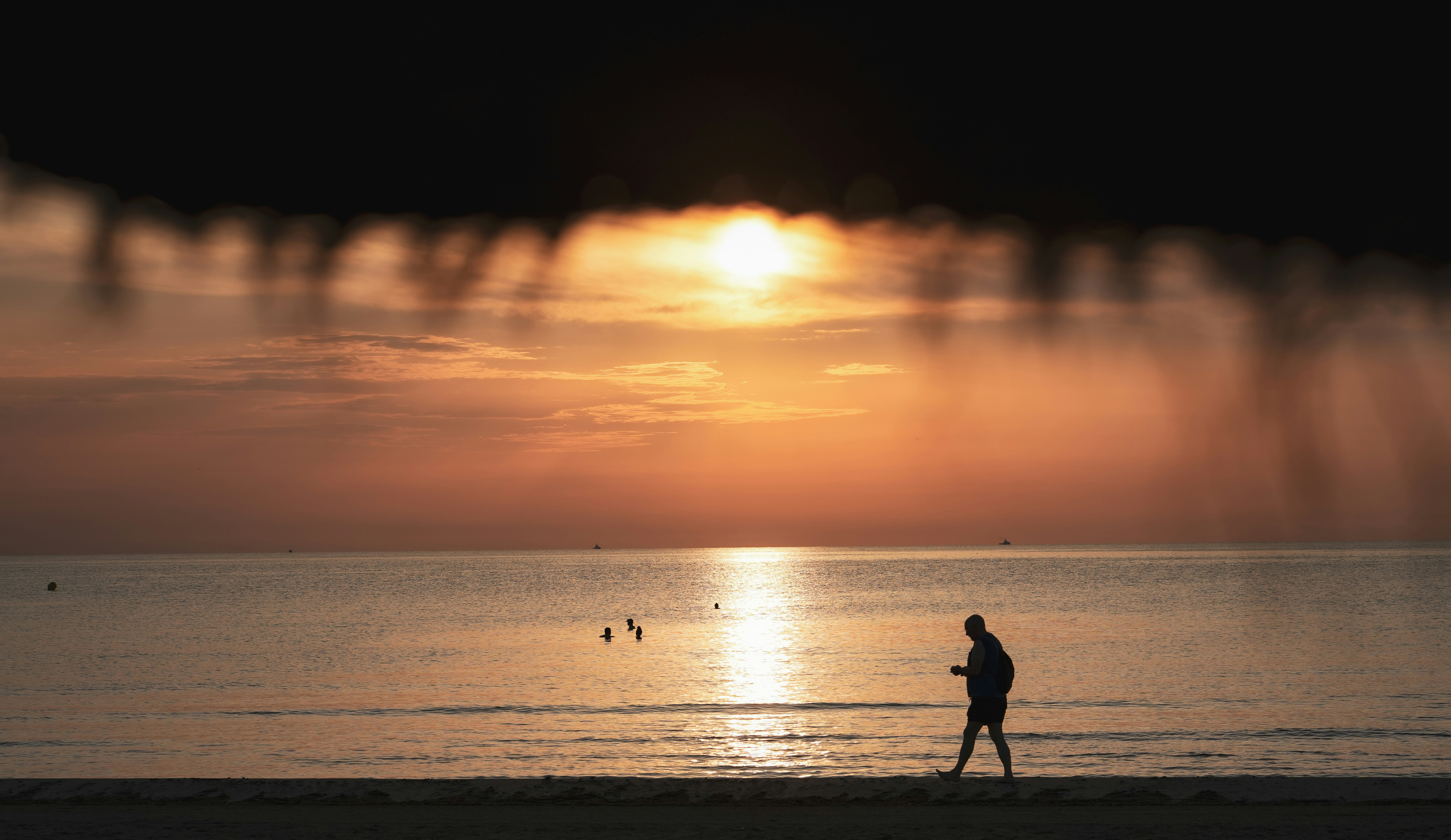 Man walks on beach at sunset.