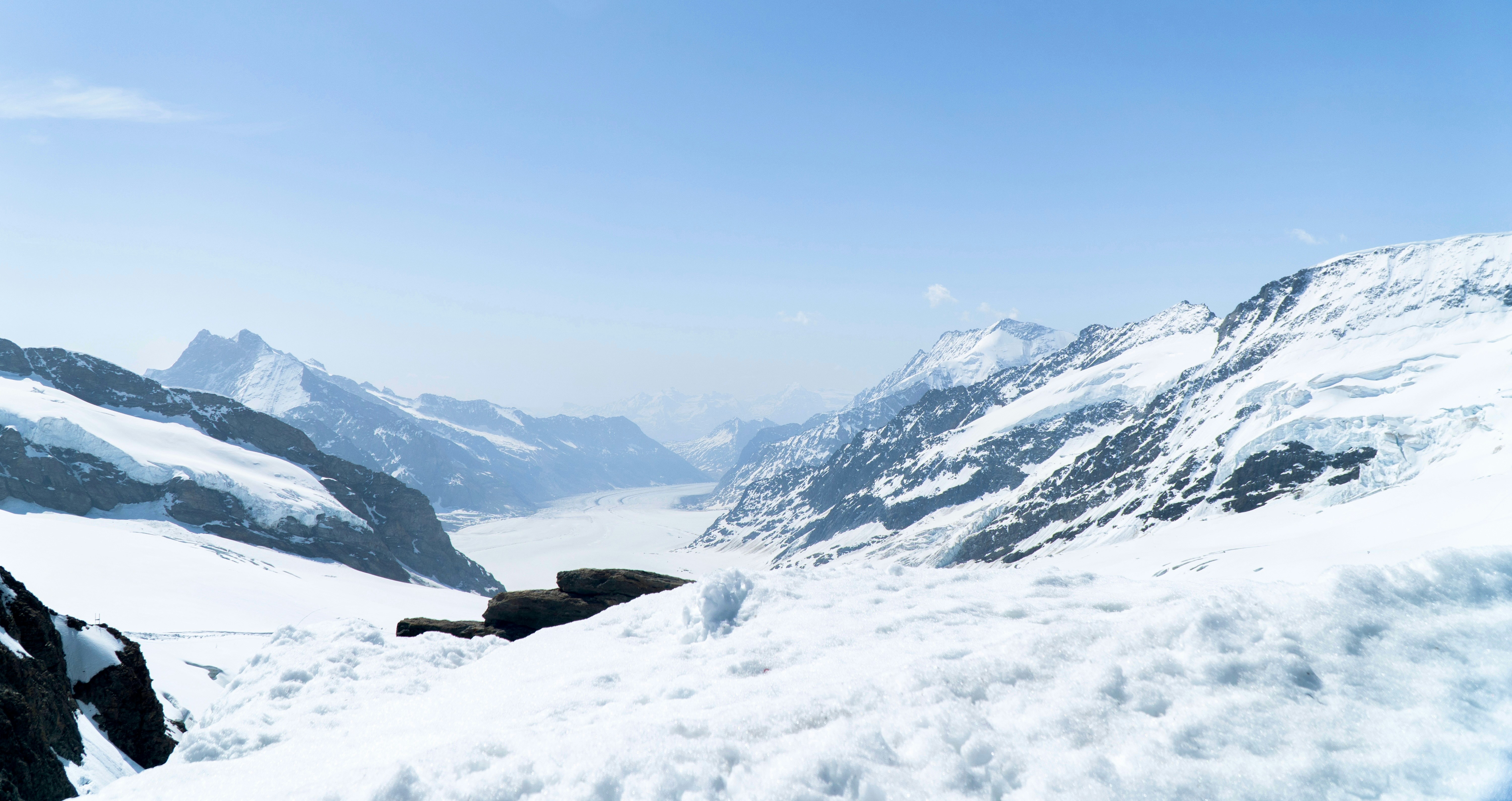 Snowy mountains stretch out under a clear, blue sky.