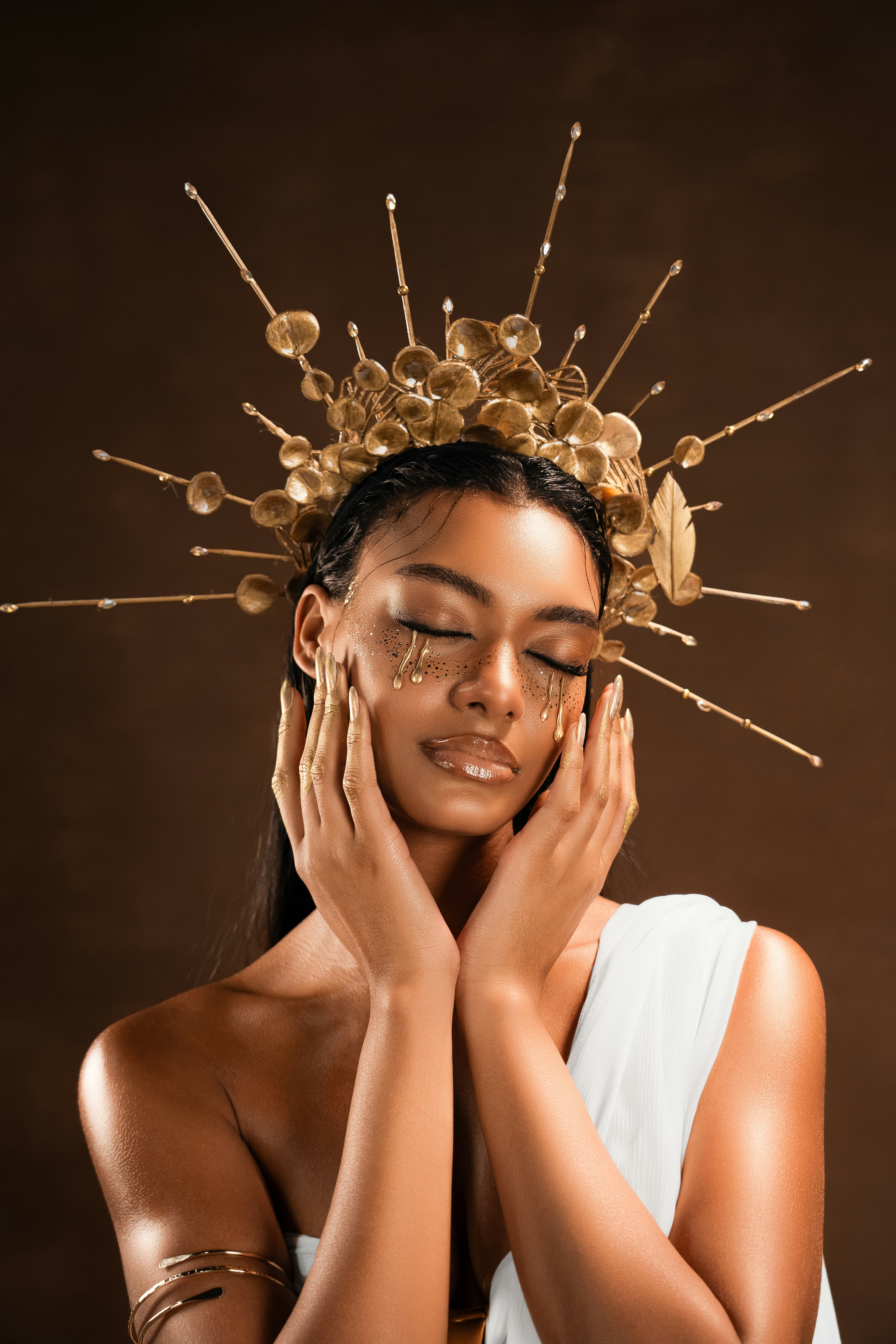 Frau mit goldenem Make-up und verzierter Kopfbedeckung.