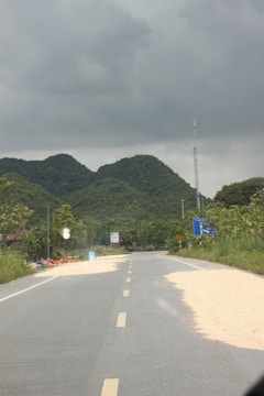 A road leads toward mountains under a stormy sky.
