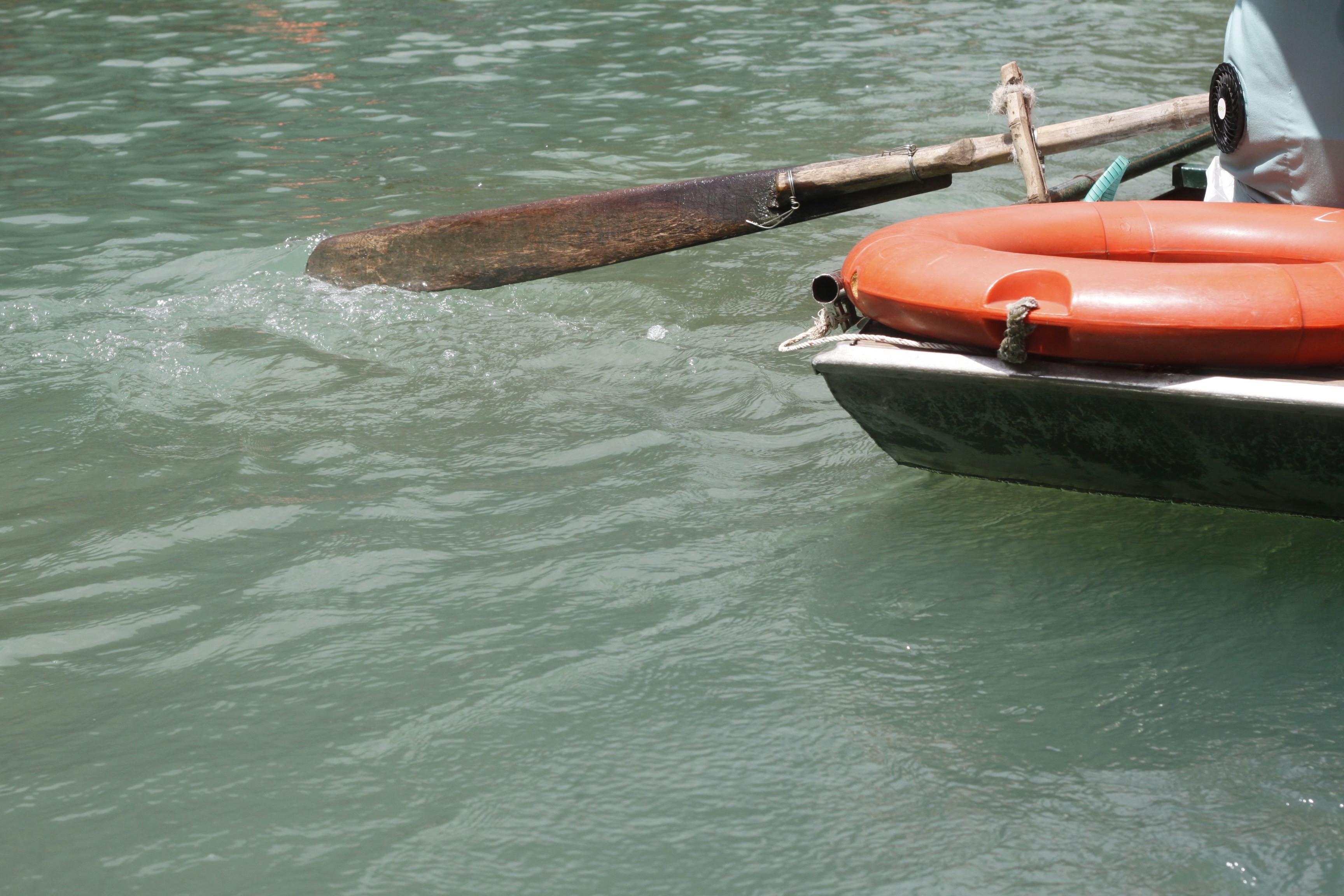 Boat with a life preserver and oar on the water.