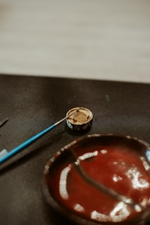 Paintbrush in a container near a painted bowl.