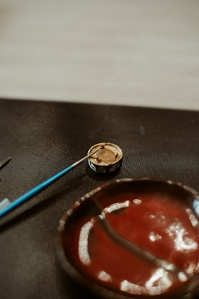 Paintbrush in a container near a painted bowl.