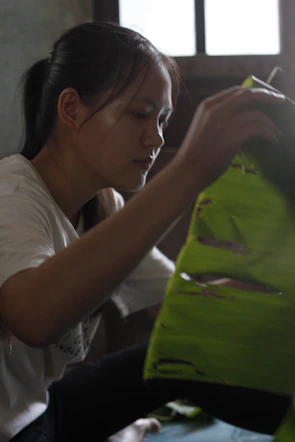 Woman carefully arranging a green leaf.