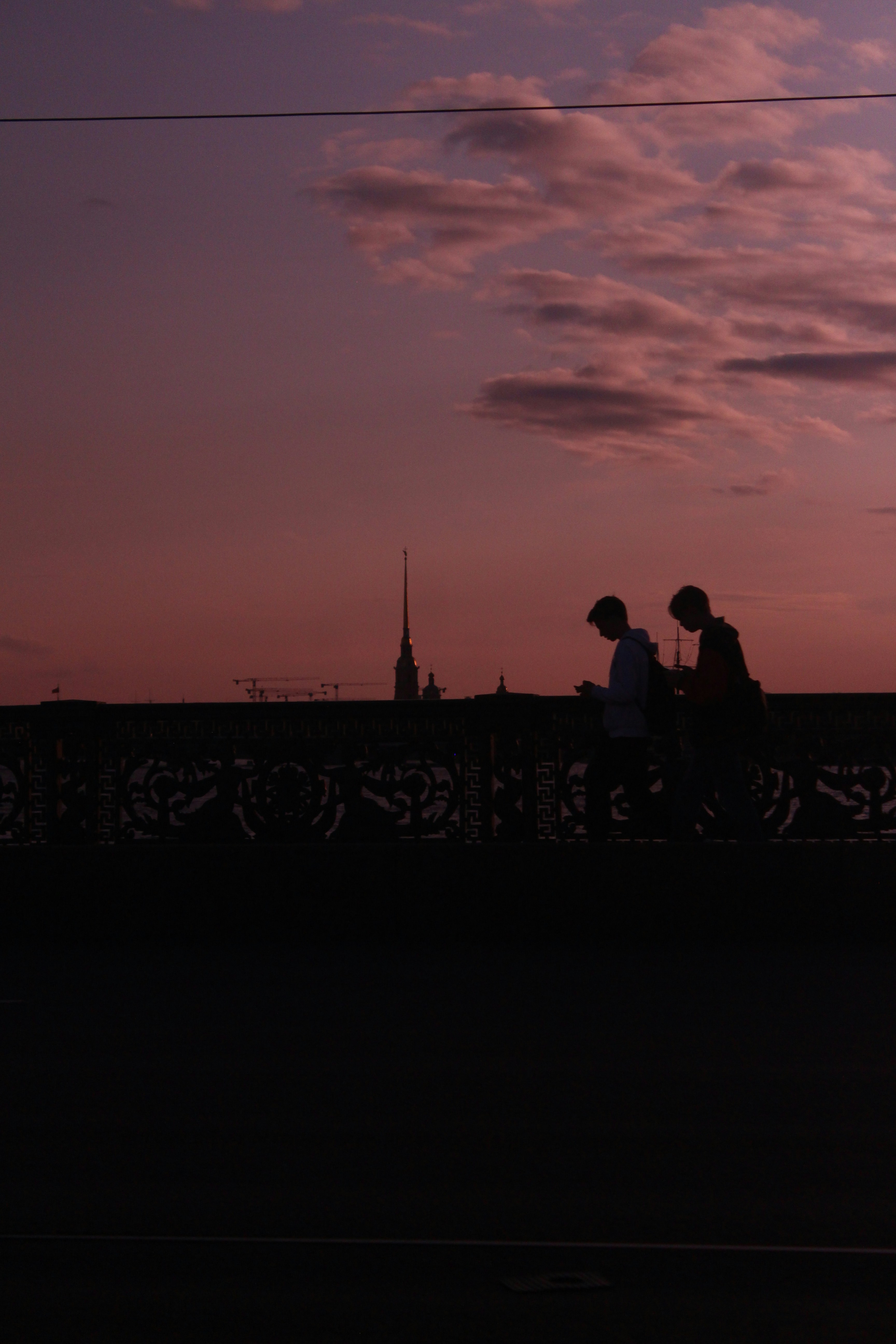 Silhouetted people on a bridge at sunset.
