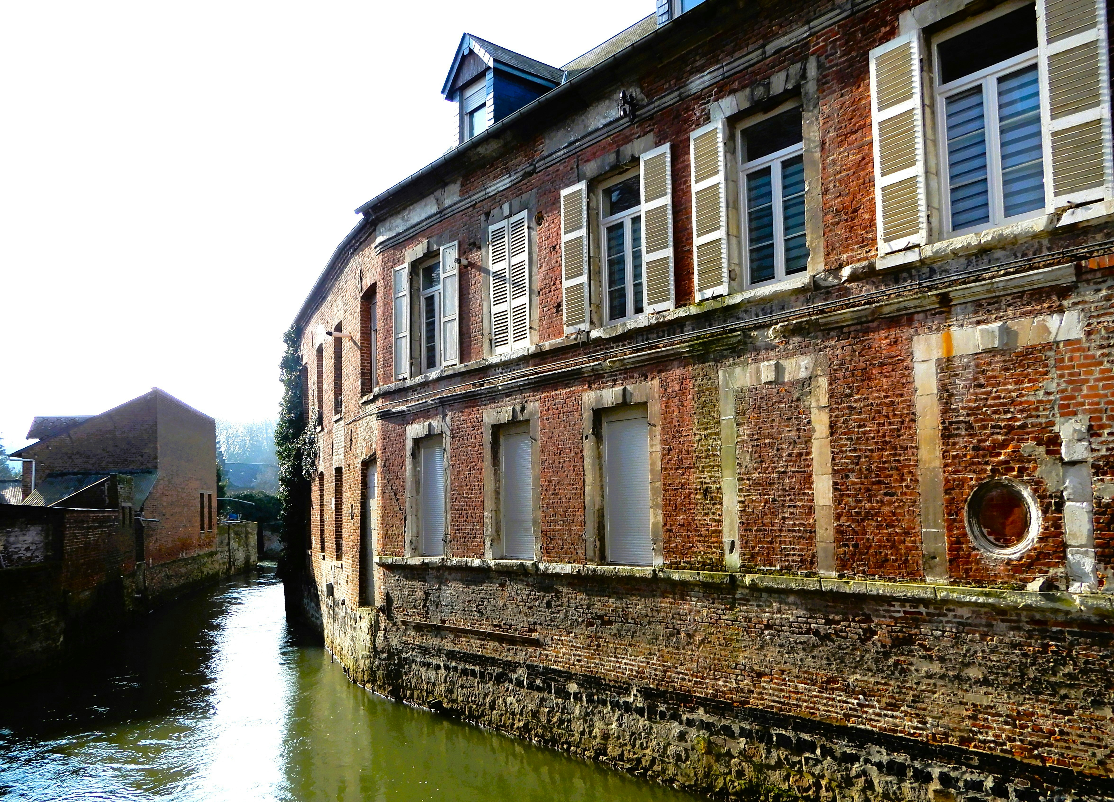 An old brick building sits on a canal.