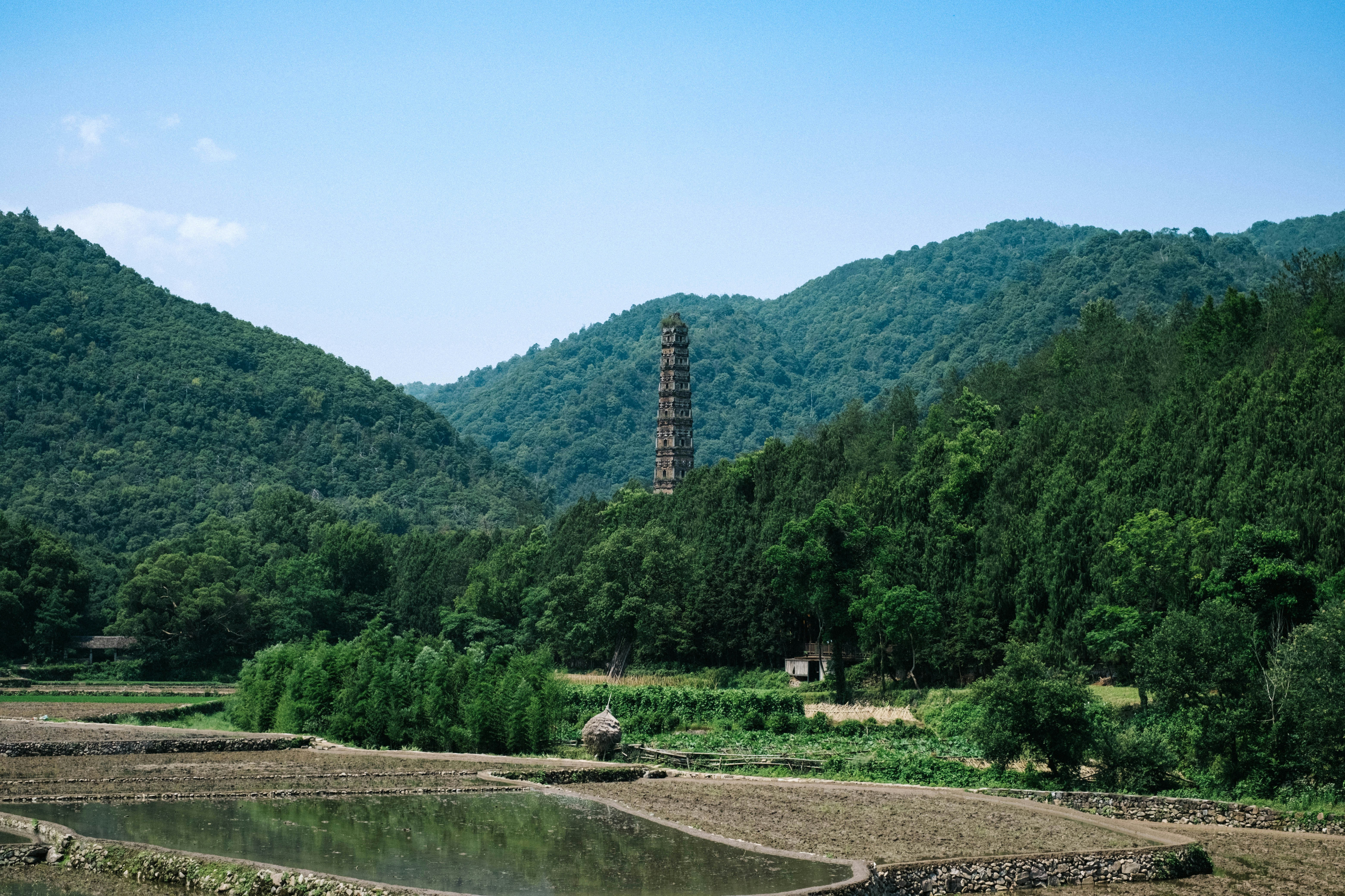 Ancient tower stands amidst lush, green mountains.