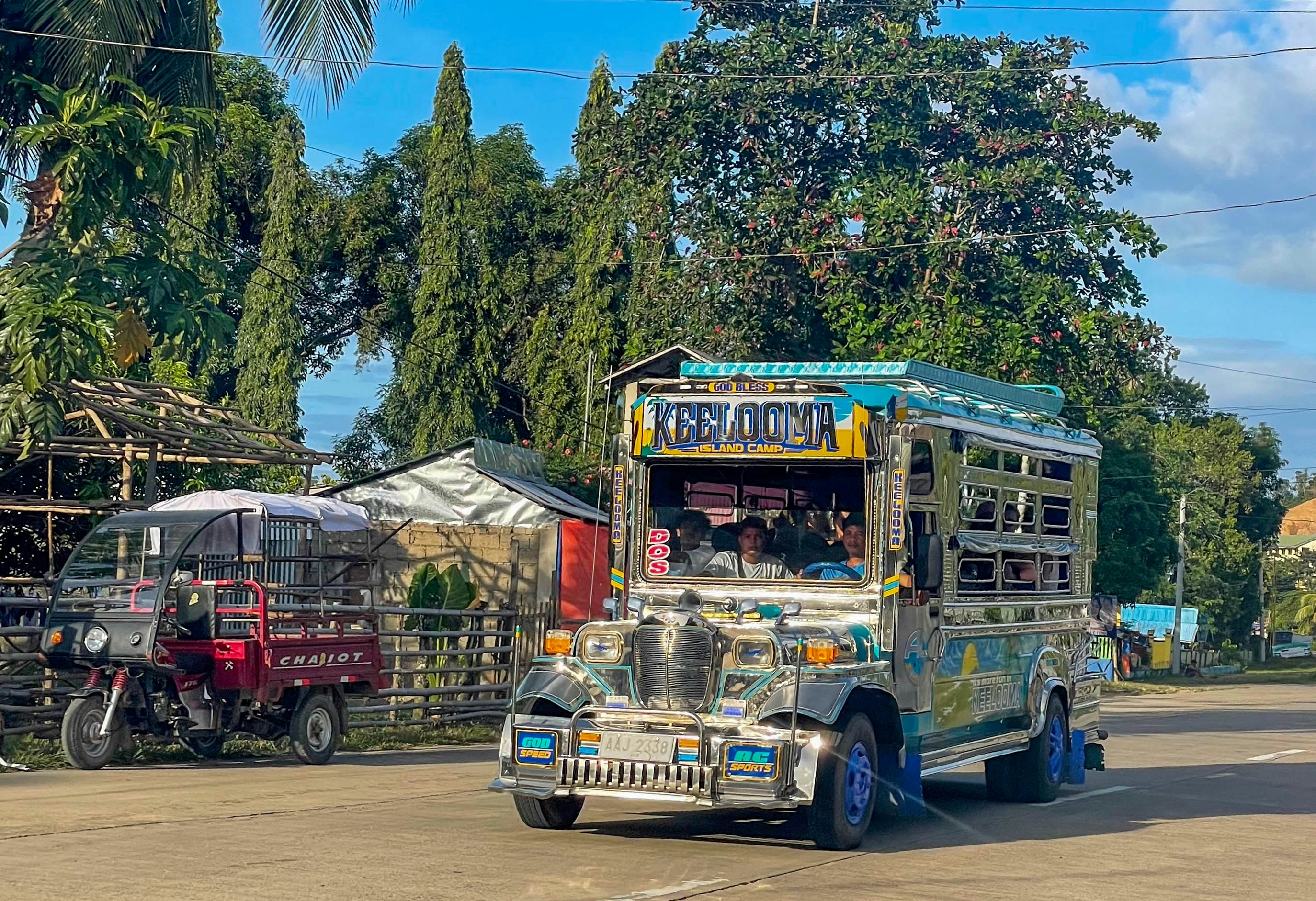 A colorful jeepney on a road with trees.