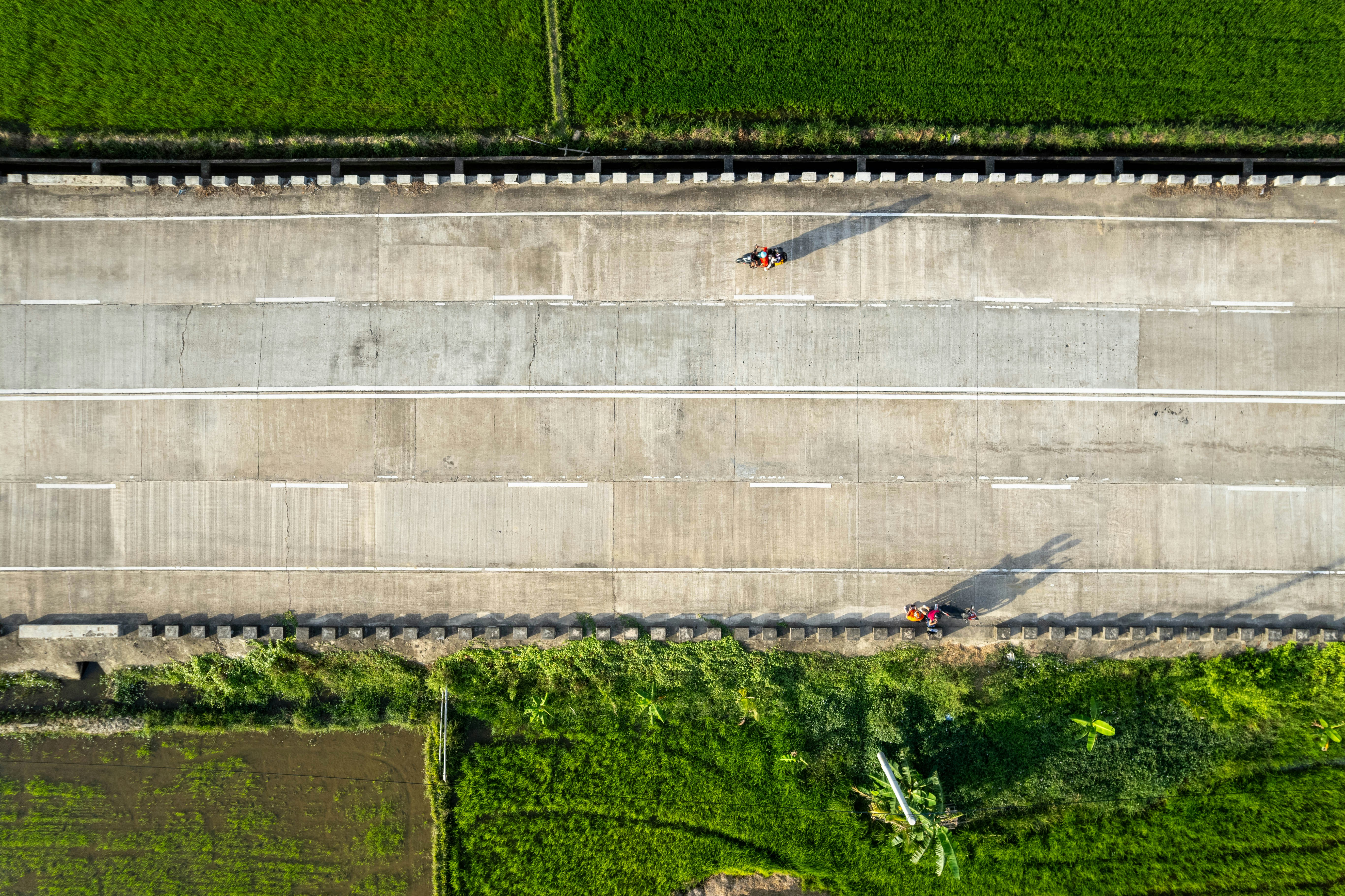 An aerial drone shot of a major new highway interchange under construction on a bright, sunny day, symbolizing large-scale infrastructure growth.