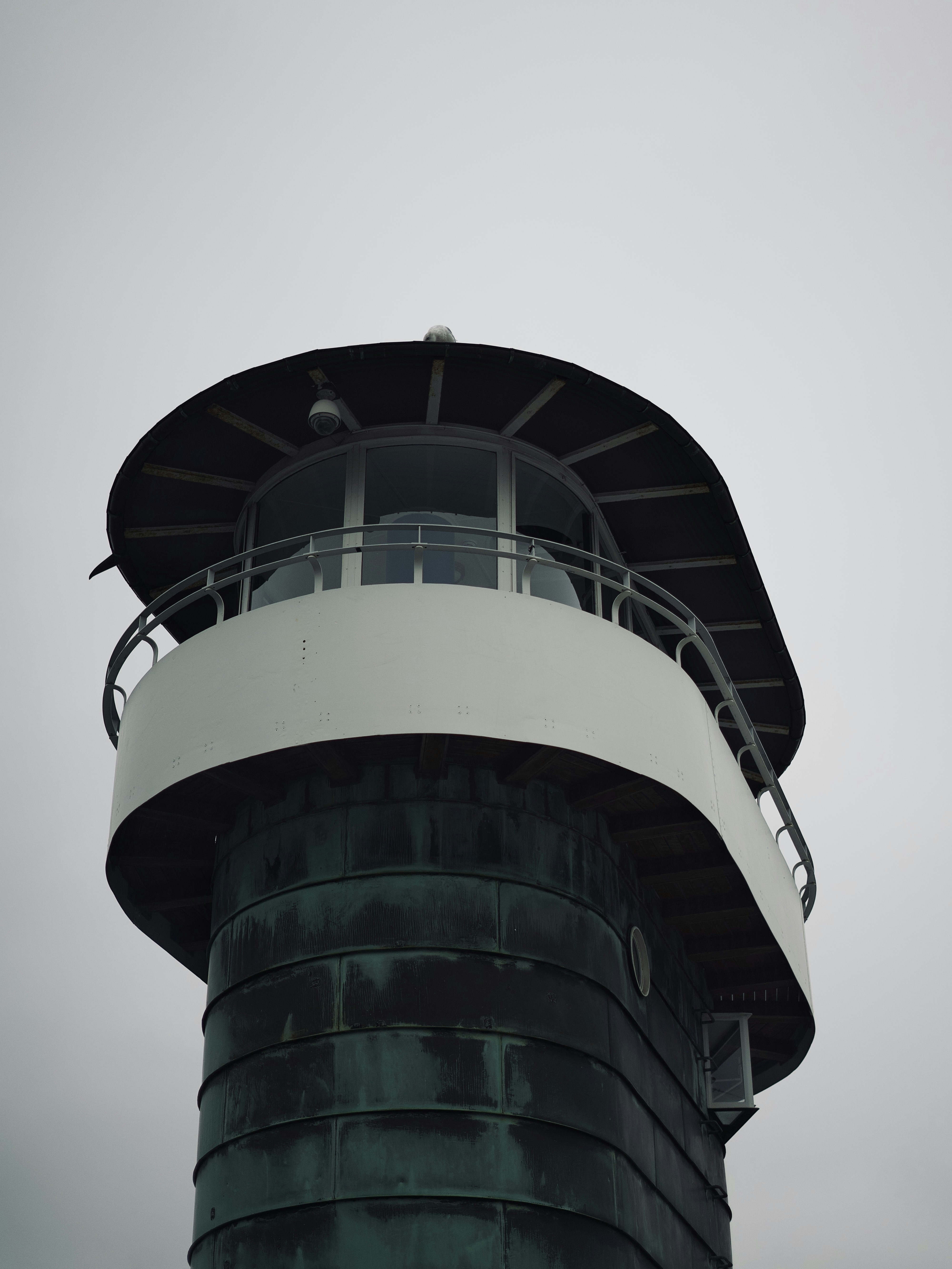 Lighthouse top against a cloudy, grey sky.