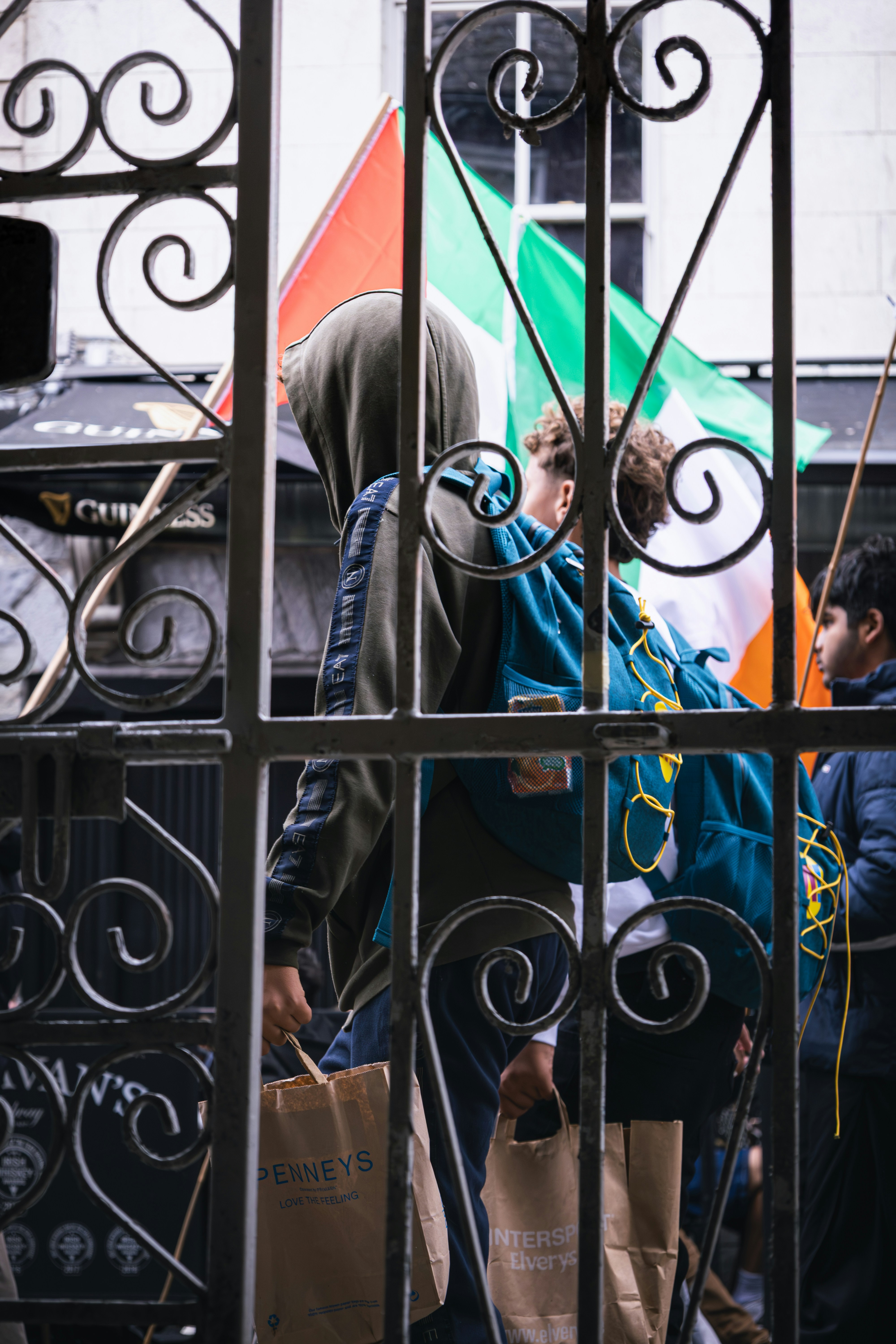 People are walking behind a gate with irish flags