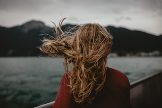 Wind blows a girl's hair near the water.