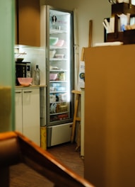 A refrigerator in a kitchen holds various food items.