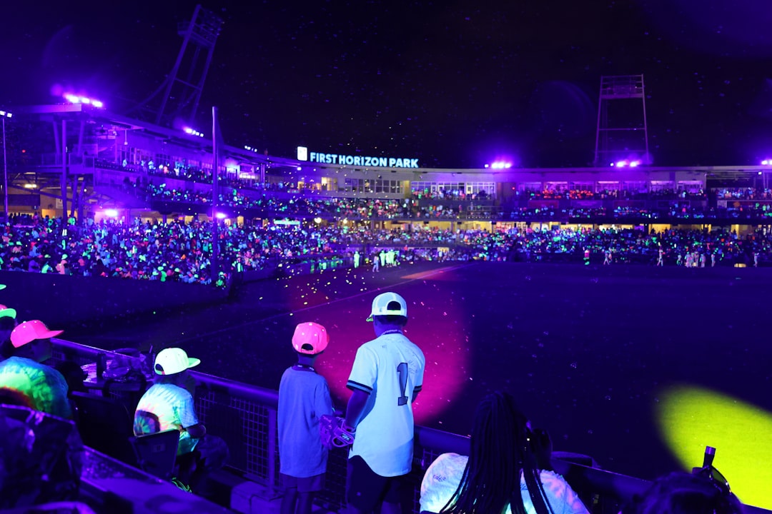 Nighttime baseball game with glowing spectators.