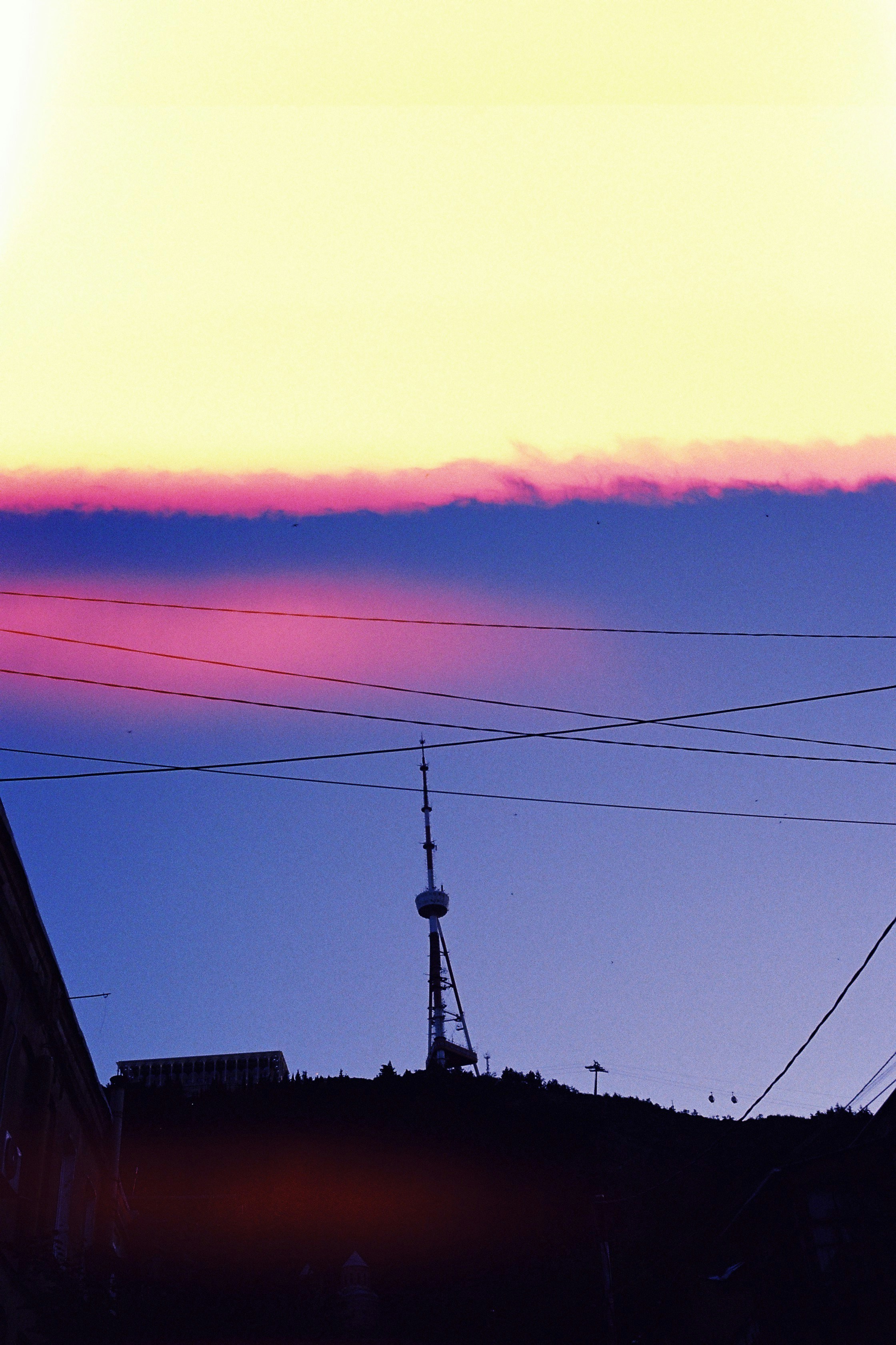Evening sky silhouettes a tower on a hill