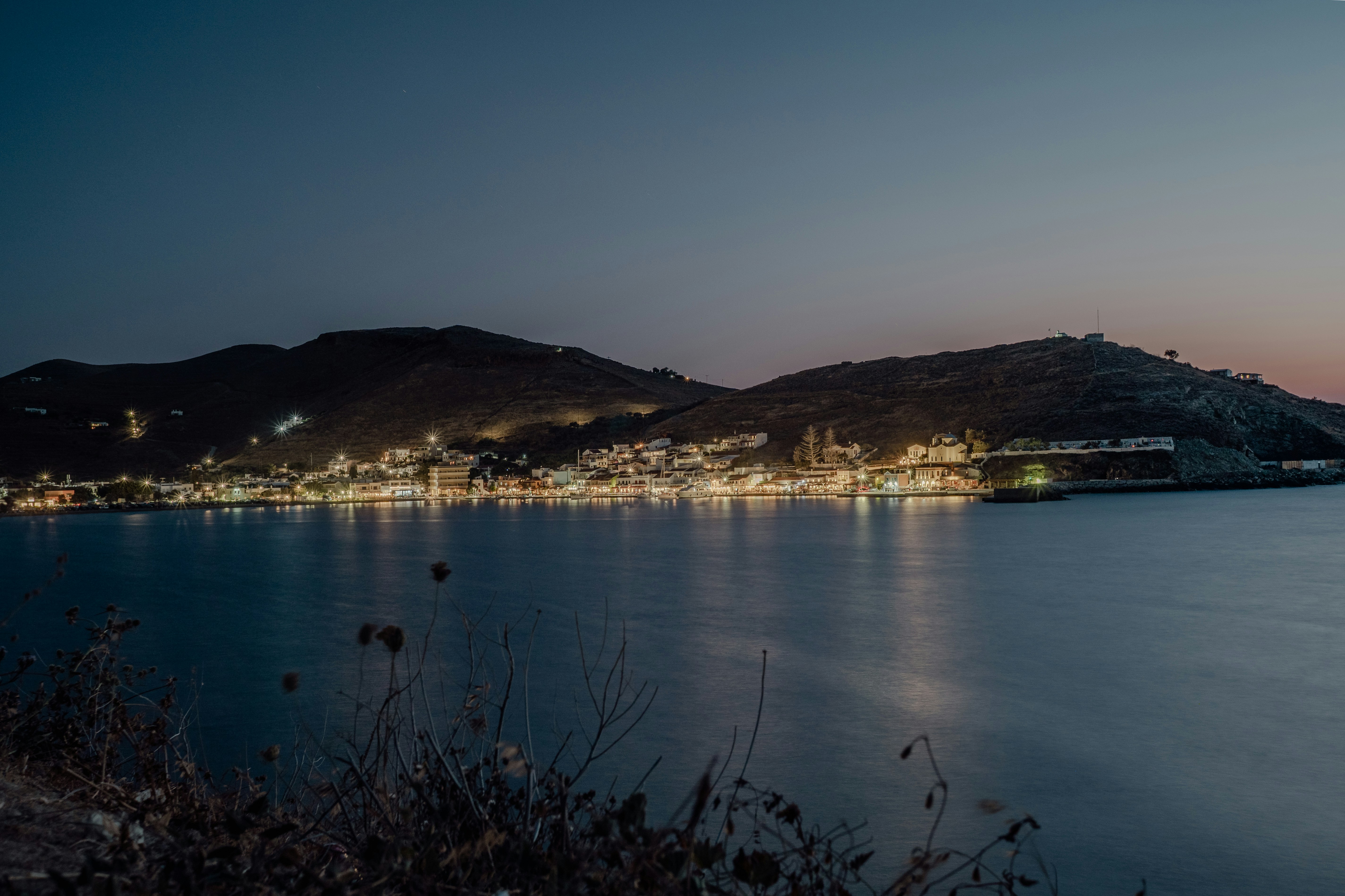 City lights shimmer across the water at dusk.