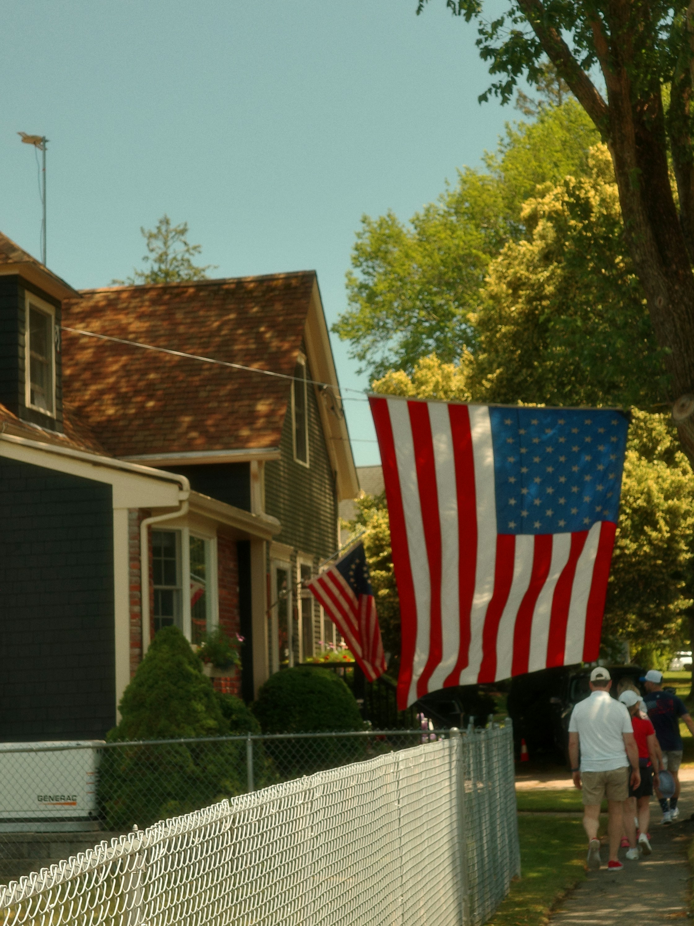 American flags hang outside a house on a sunny day.