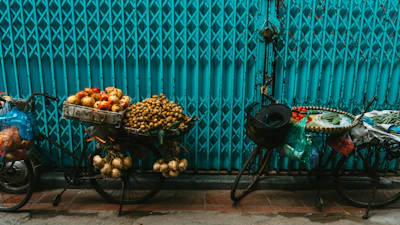 Bicycles with various fruits are displayed on the street.