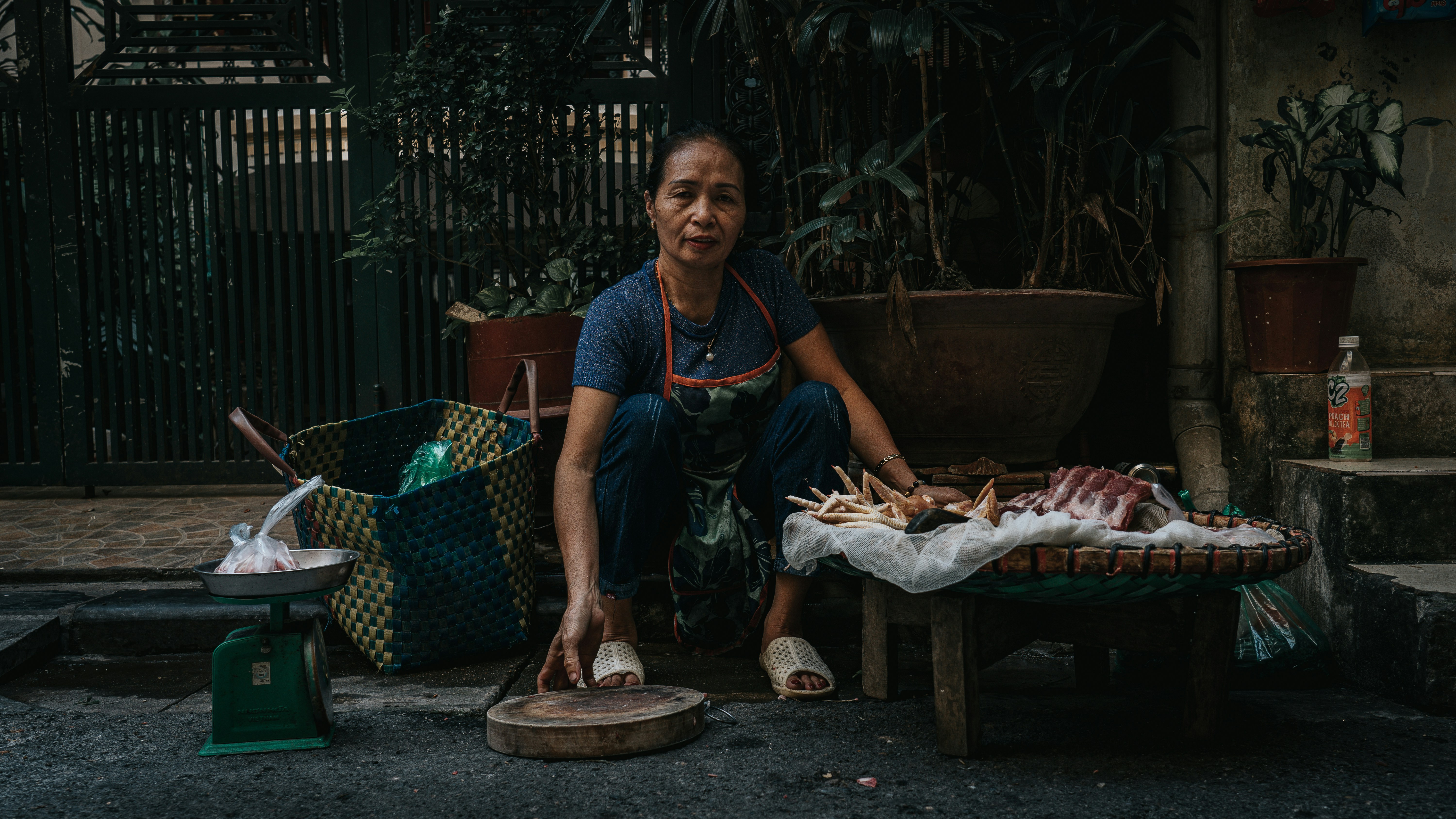 A woman sells food on a sidewalk.