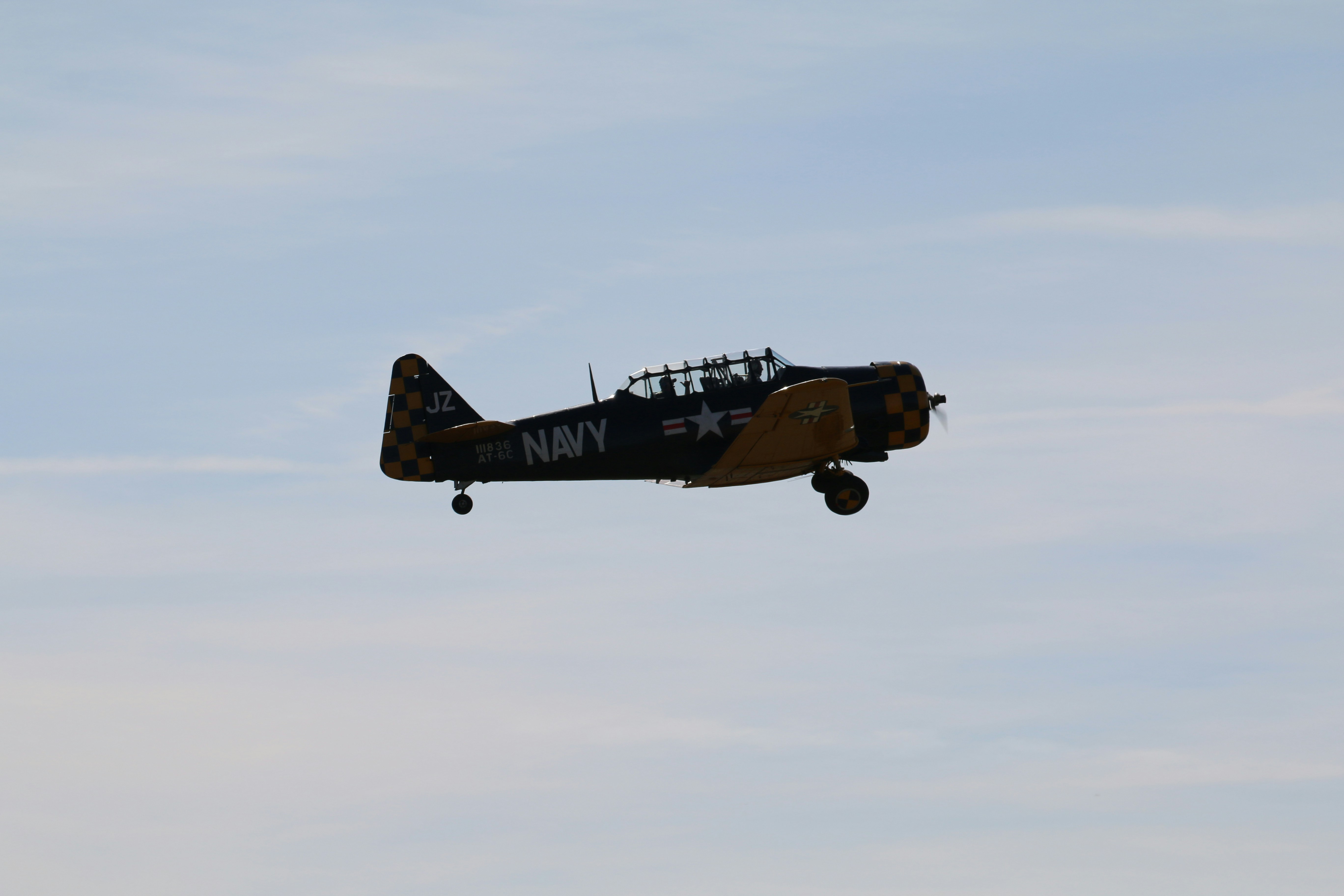 A vintage navy plane flies through the sky.