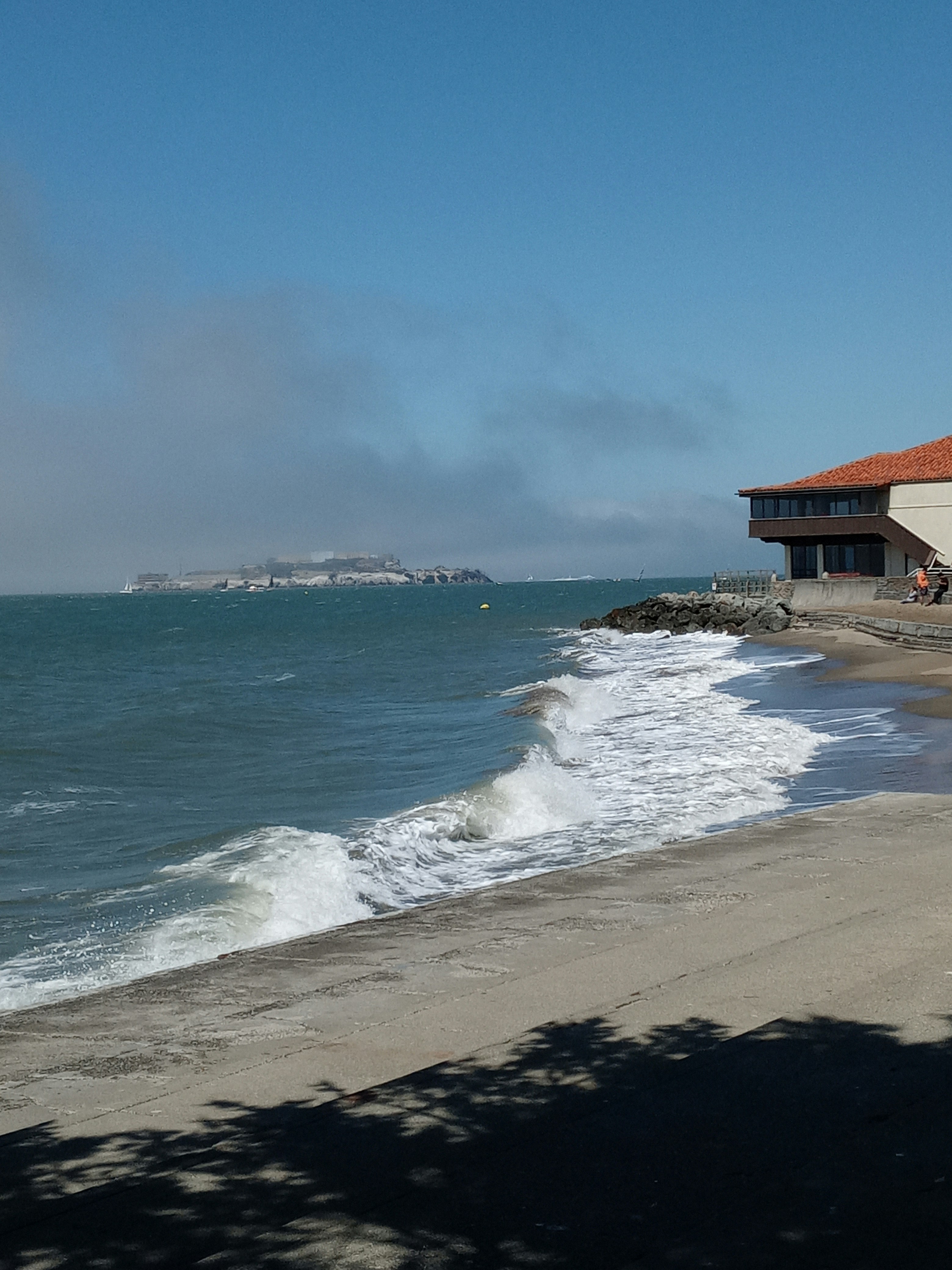 Waves crash on the shore near a building.