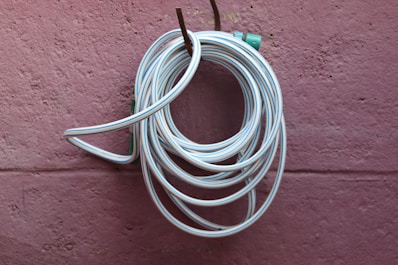 A white hose is coiled and hung on a wall.
