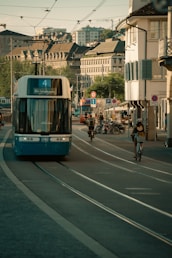 A blue tram moves through a city street.
